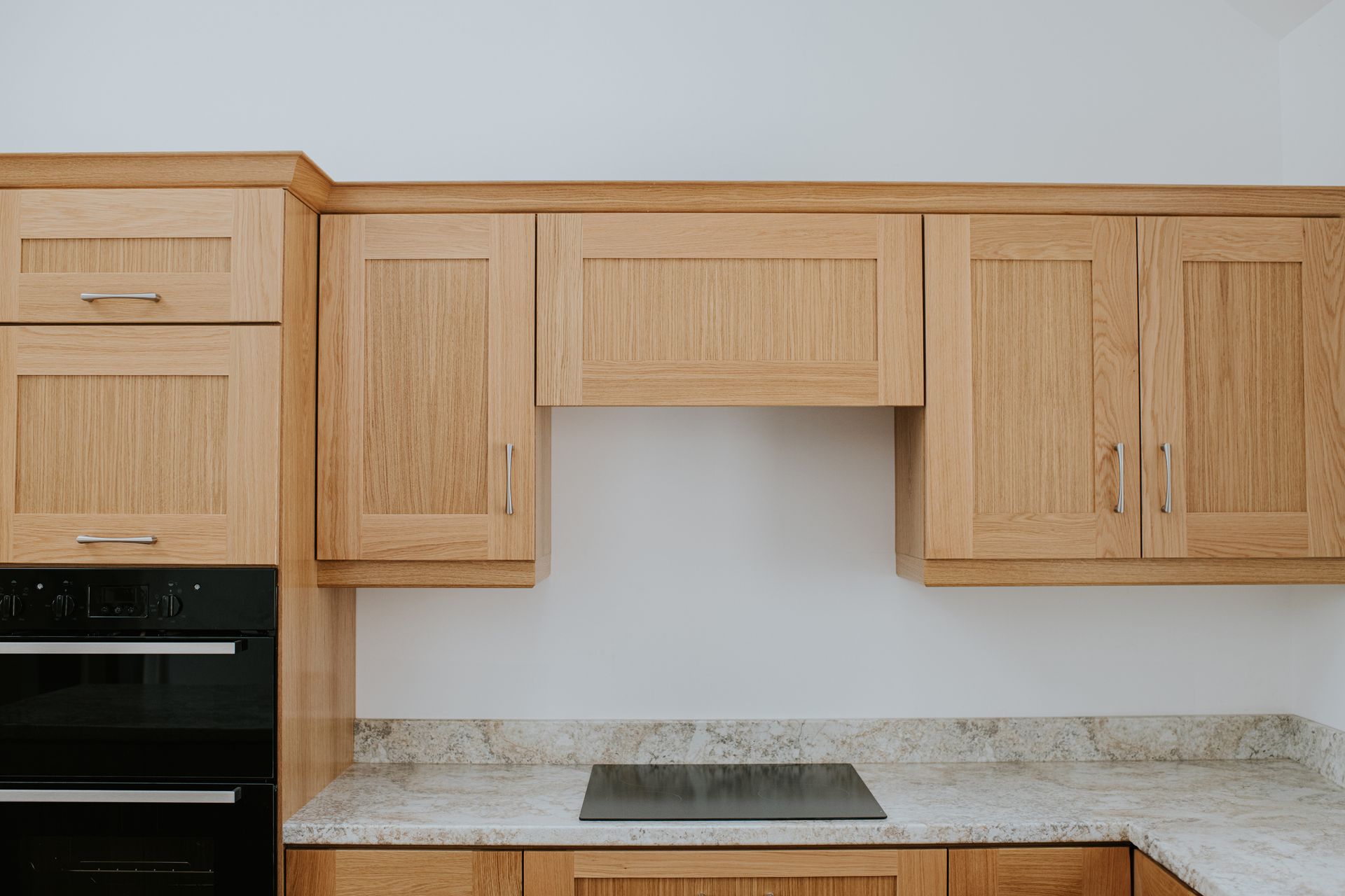Oak kitchen cabinets with granite countertop and black oven.