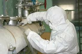 A man in a protective suit is working on a pipe.