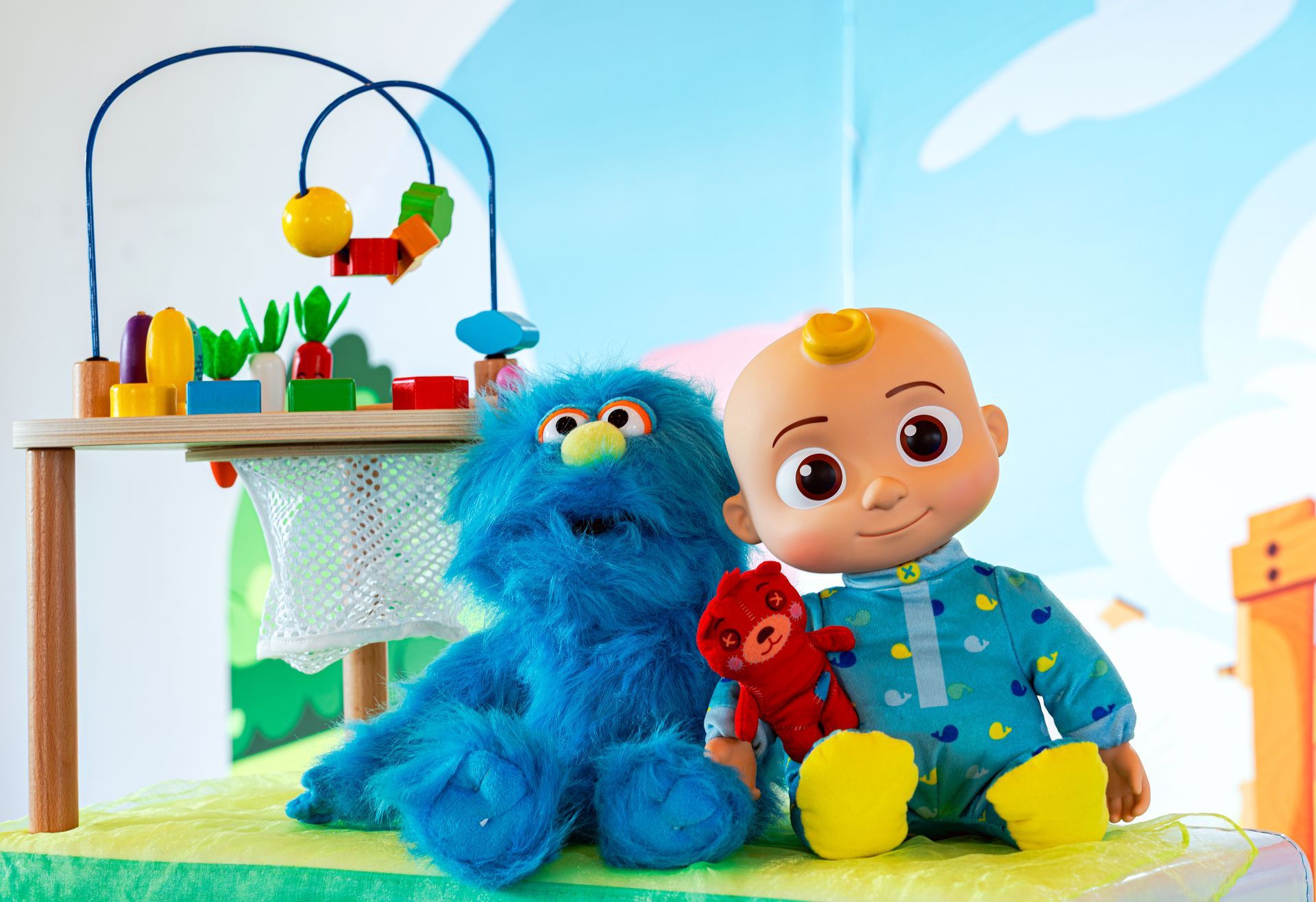 Un muñeco está sentado al lado de un monstruo de galletas y personajes de Barrio Sésamo.