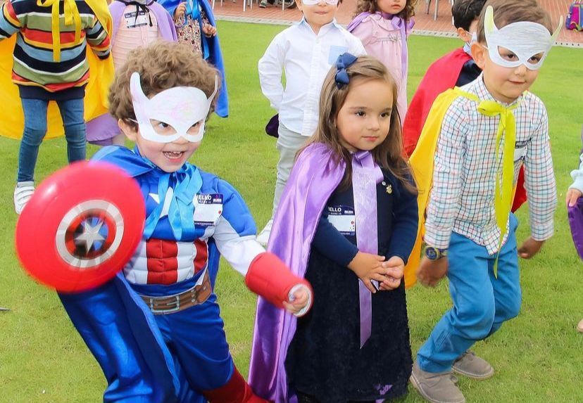 Un grupo de niños vestidos con disfraces de superhéroes están de pie en el césped.