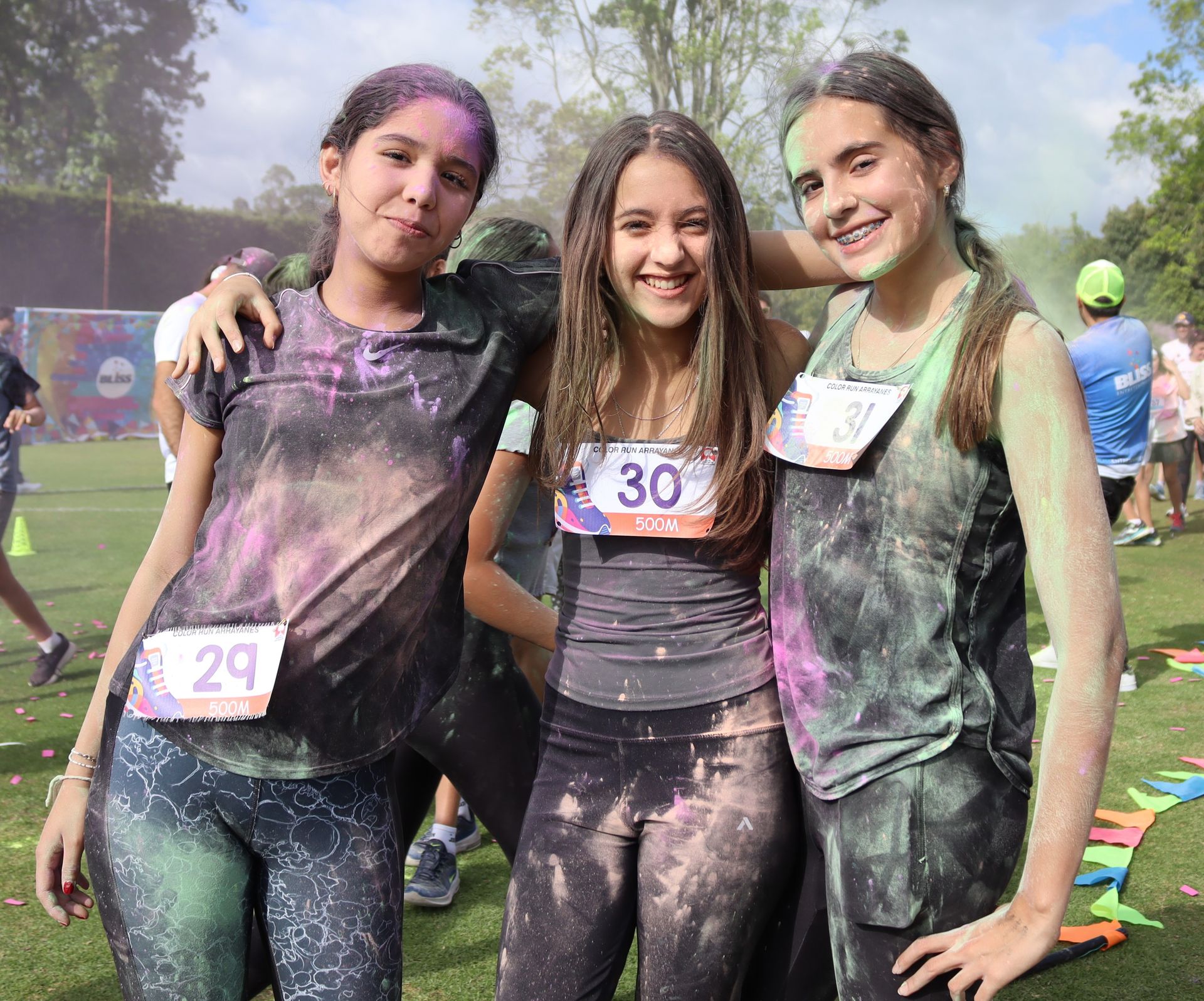 Tres chicas posan para una fotografía cubiertas de polvos de colores.