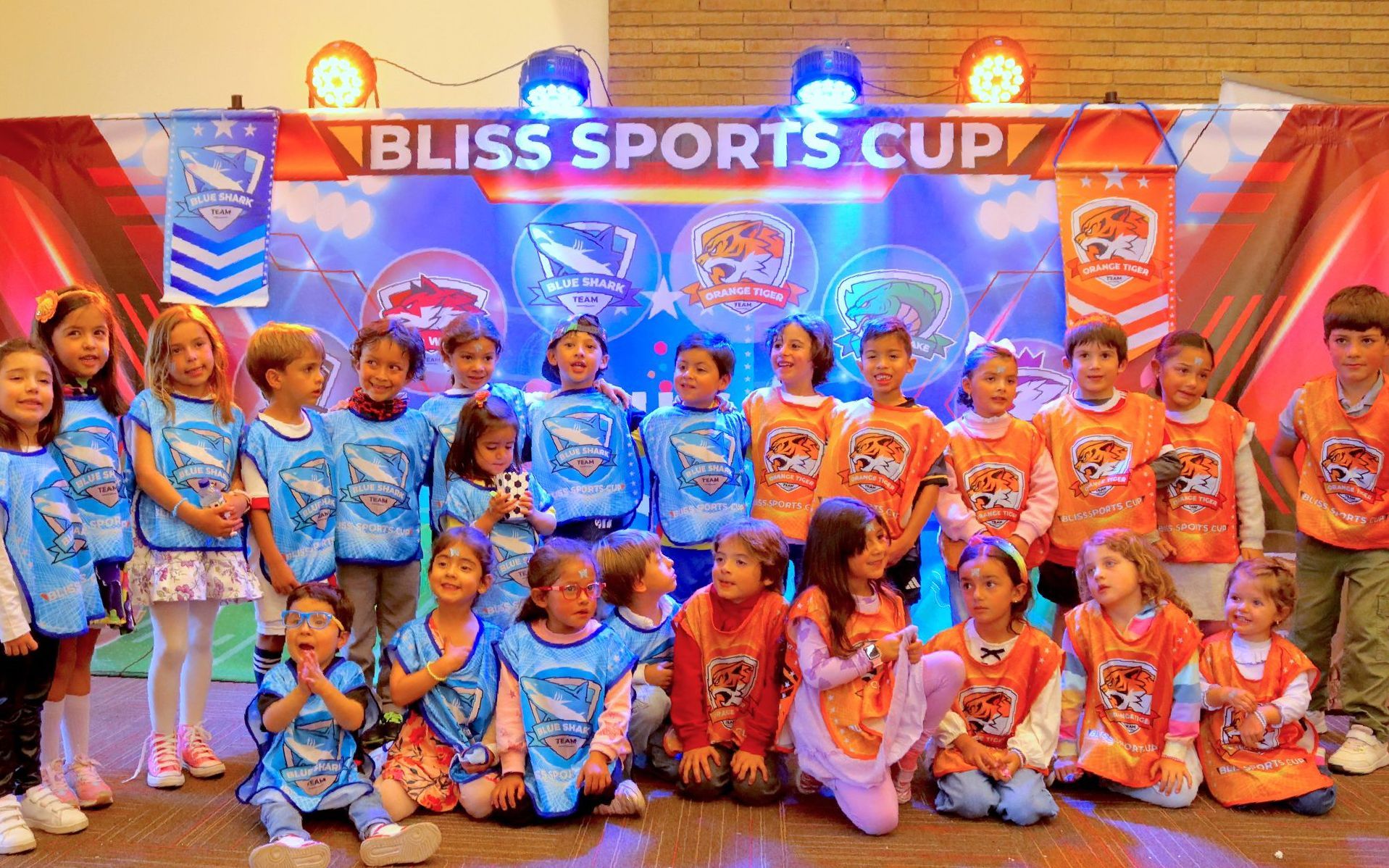 Un grupo de niños posa para una foto frente a una pancarta de la Copa Deportiva Bliss.