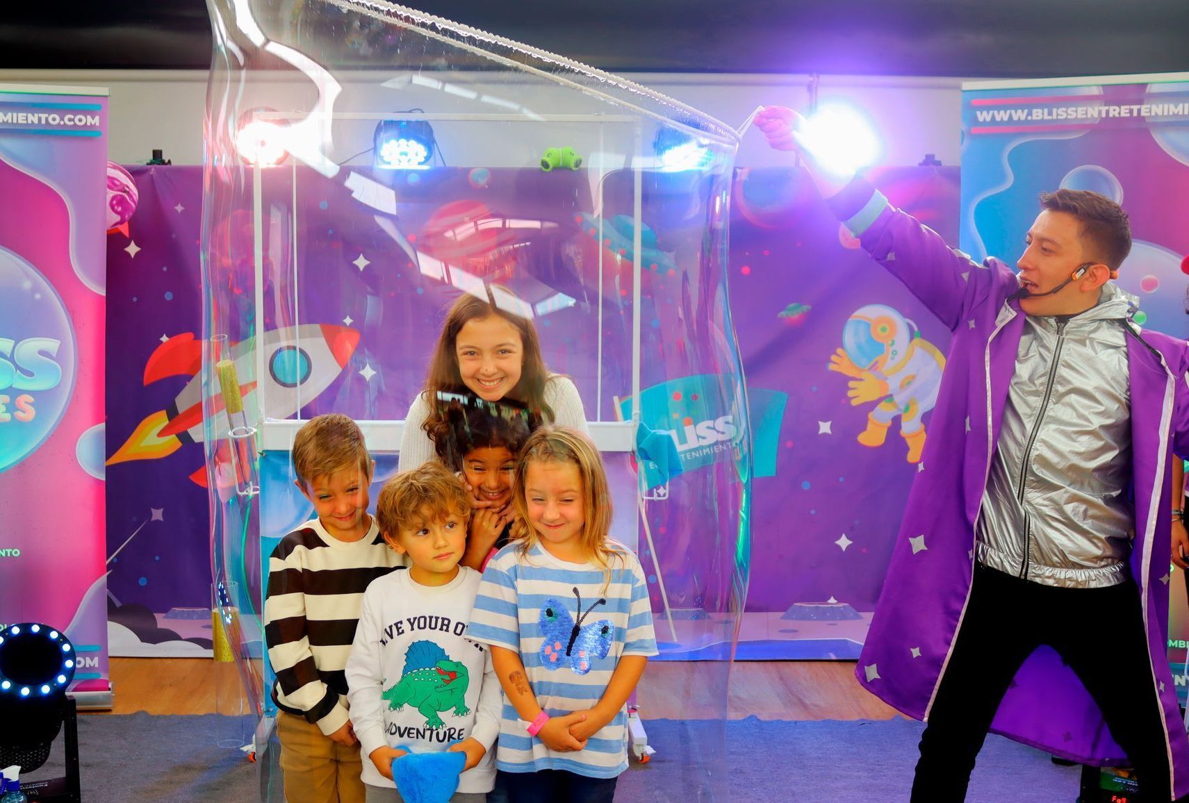 Un grupo de niños posa para una foto con un hombre con un abrigo morado.