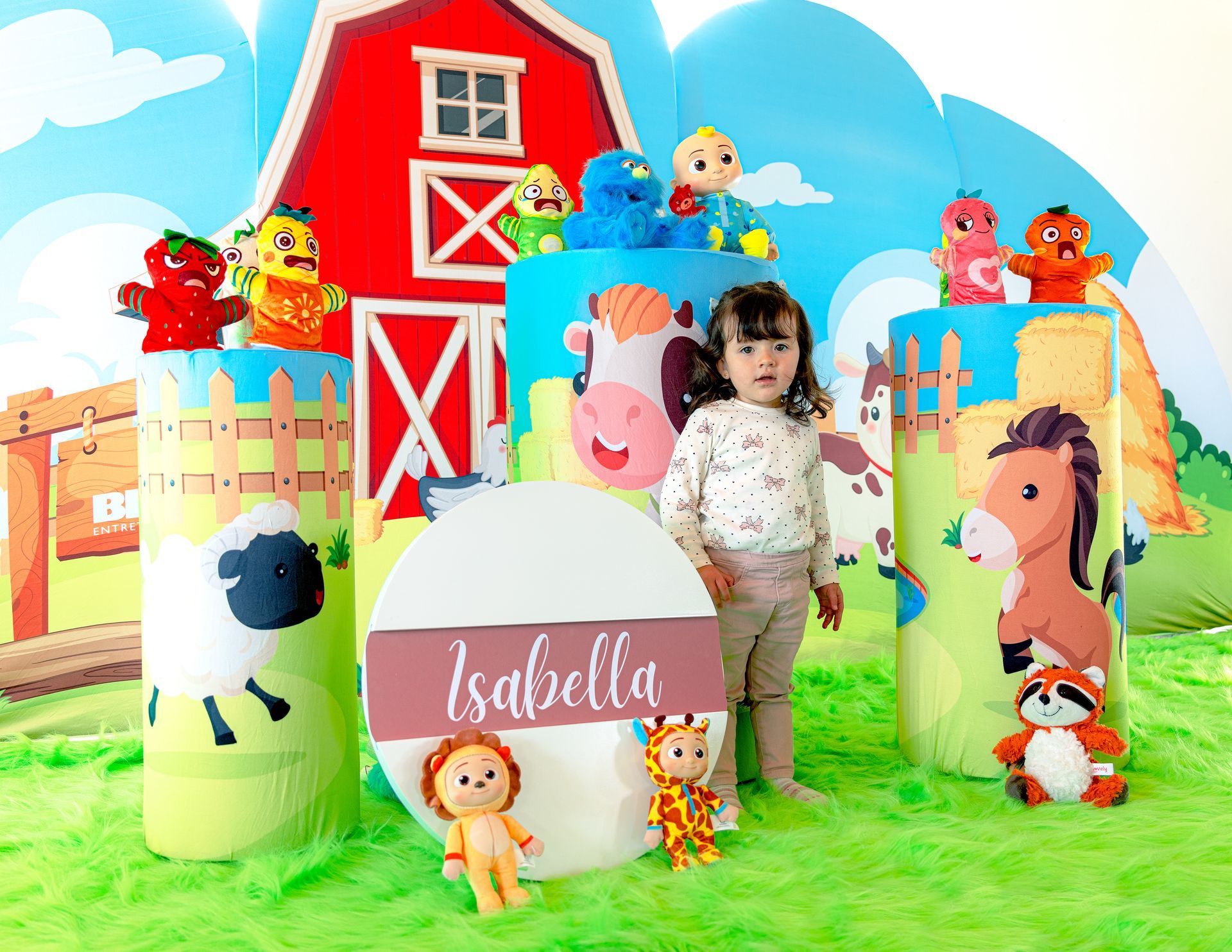 Una niña está parada frente a una escena de granja con animales de peluche.