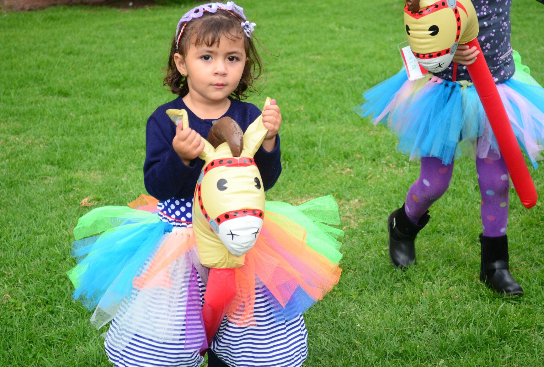 Una niña está montando un caballo saltando en la hierba.