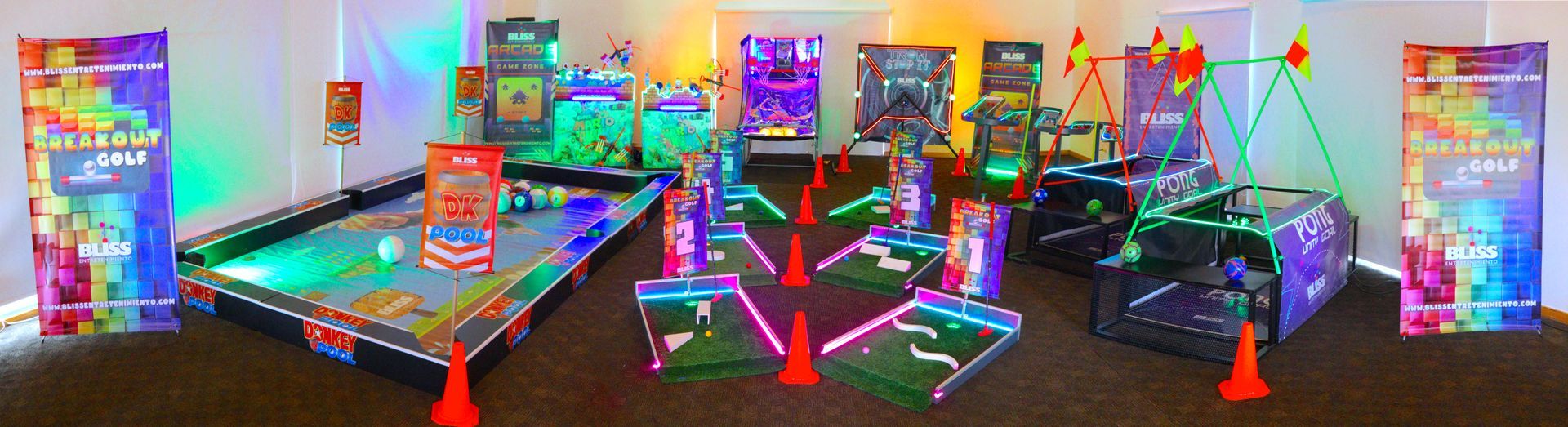 Un salón de juegos iluminado con neón que incluye minigolf, billar y otros juegos iluminados en un evento.