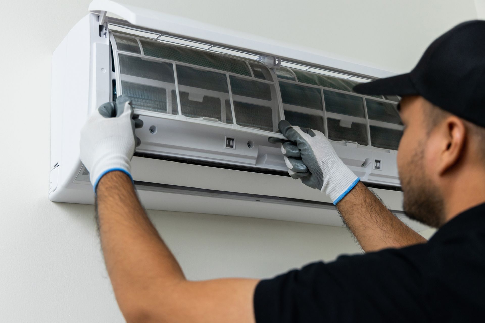 A man is cleaning an air conditioner with gloves. A man is cleaning an air conditioner with gloves.