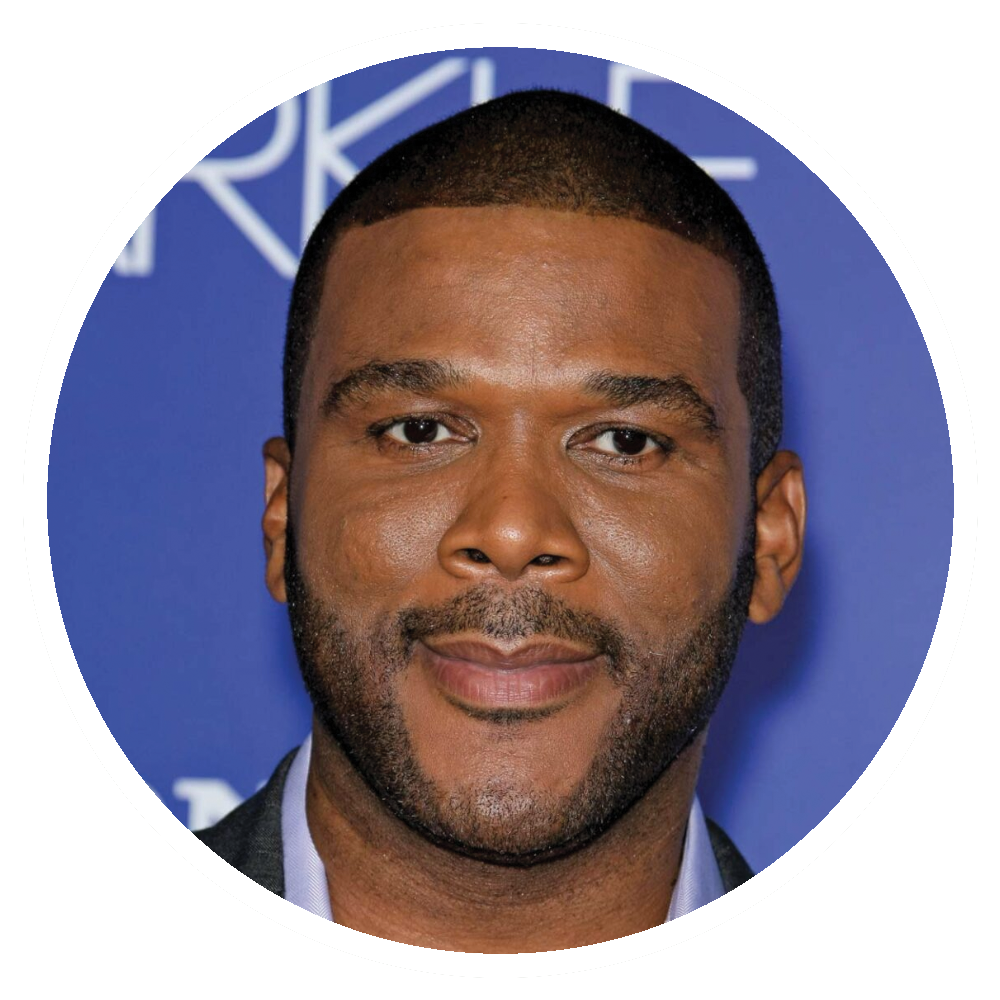 Tyler Perry with a dark complexion, wearing a suit, smiling at the camera, in front of a blue backdrop.