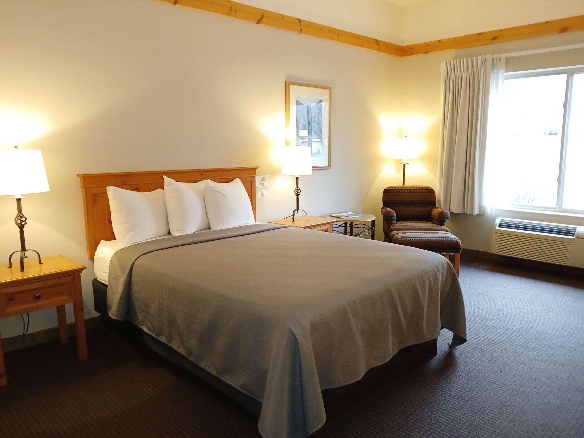 A hotel room with a king size bed and a chair