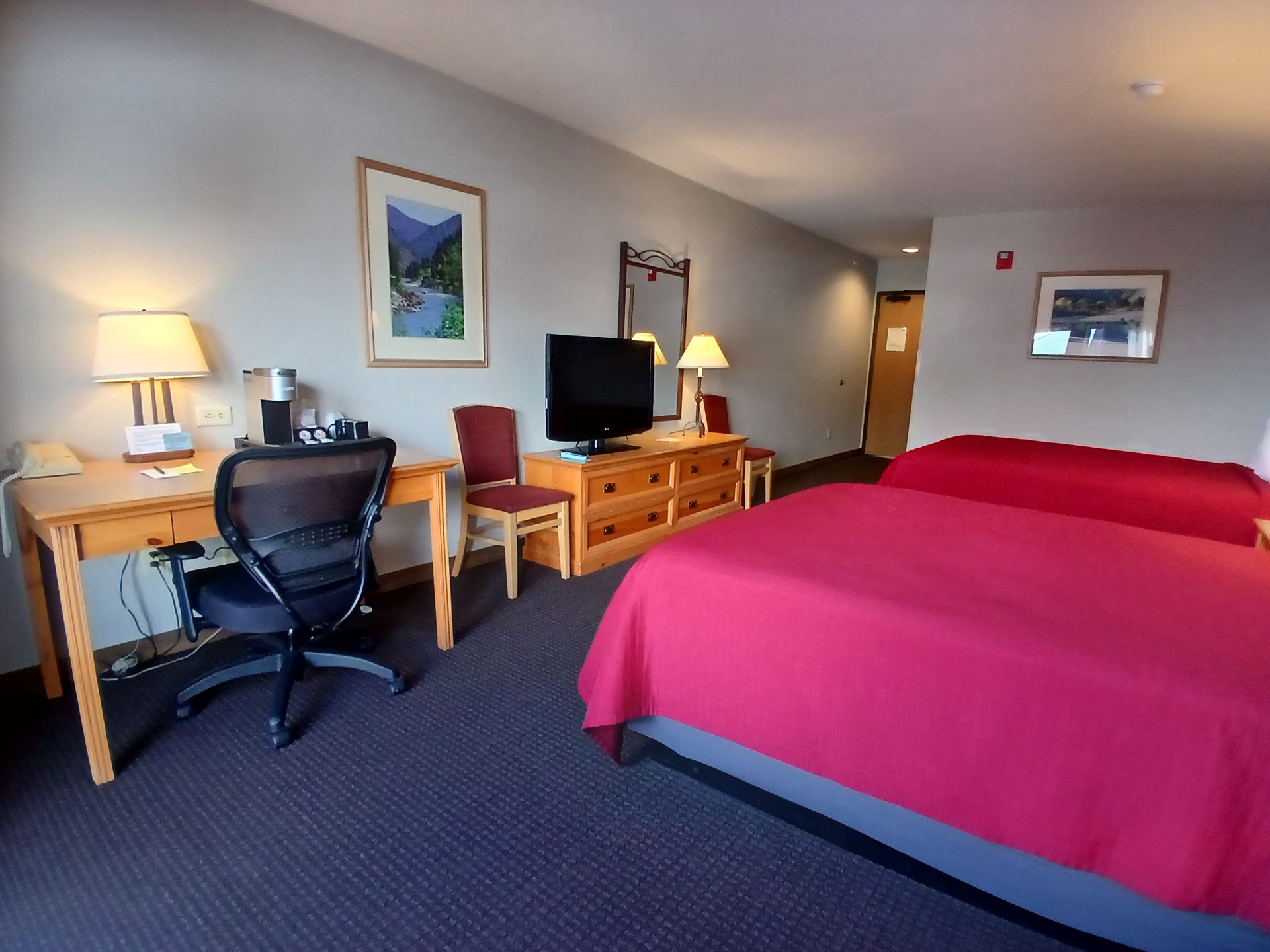 A hotel room with two beds , a desk and a television.