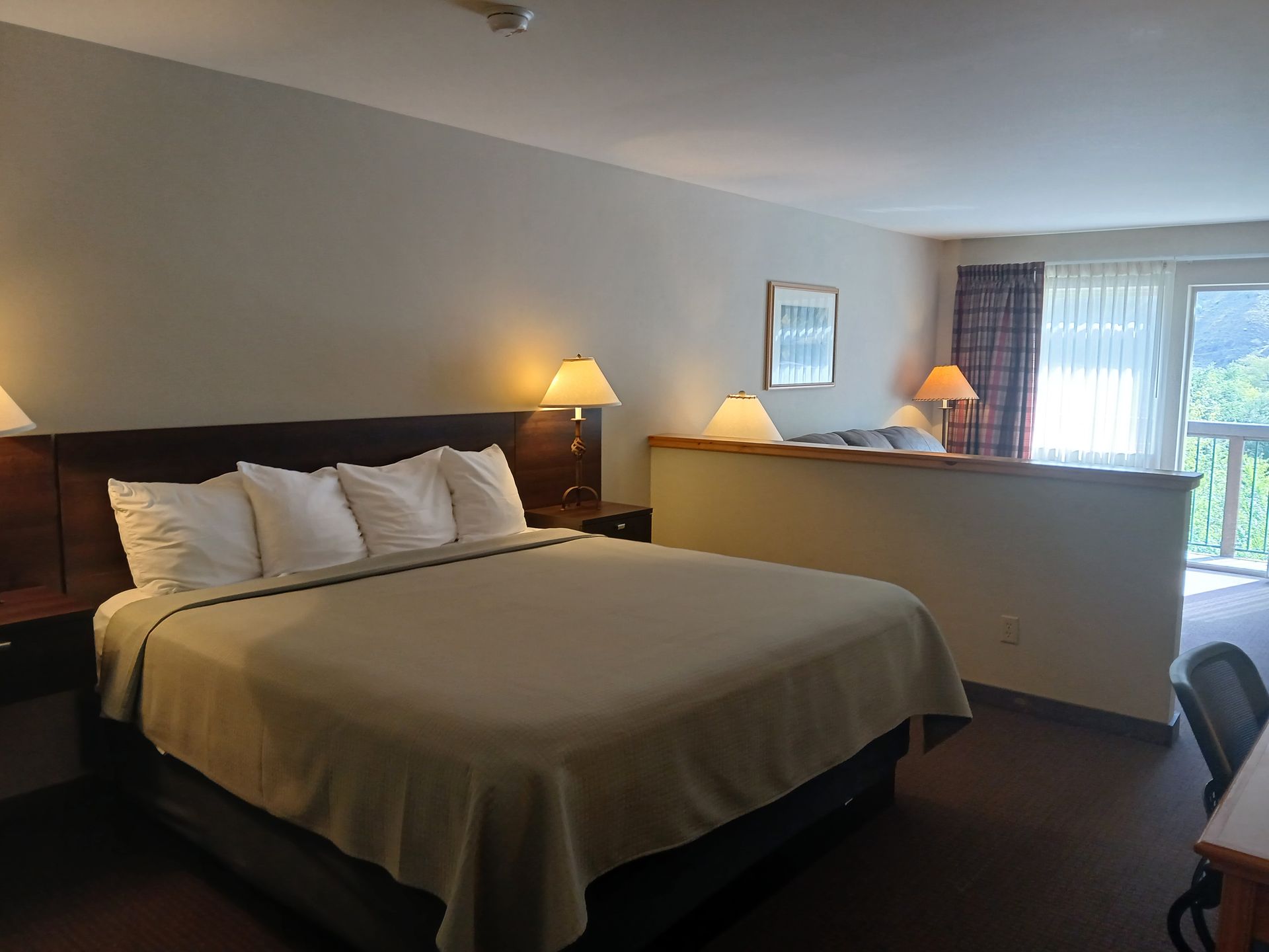 A hotel room with a king size bed and a large window.