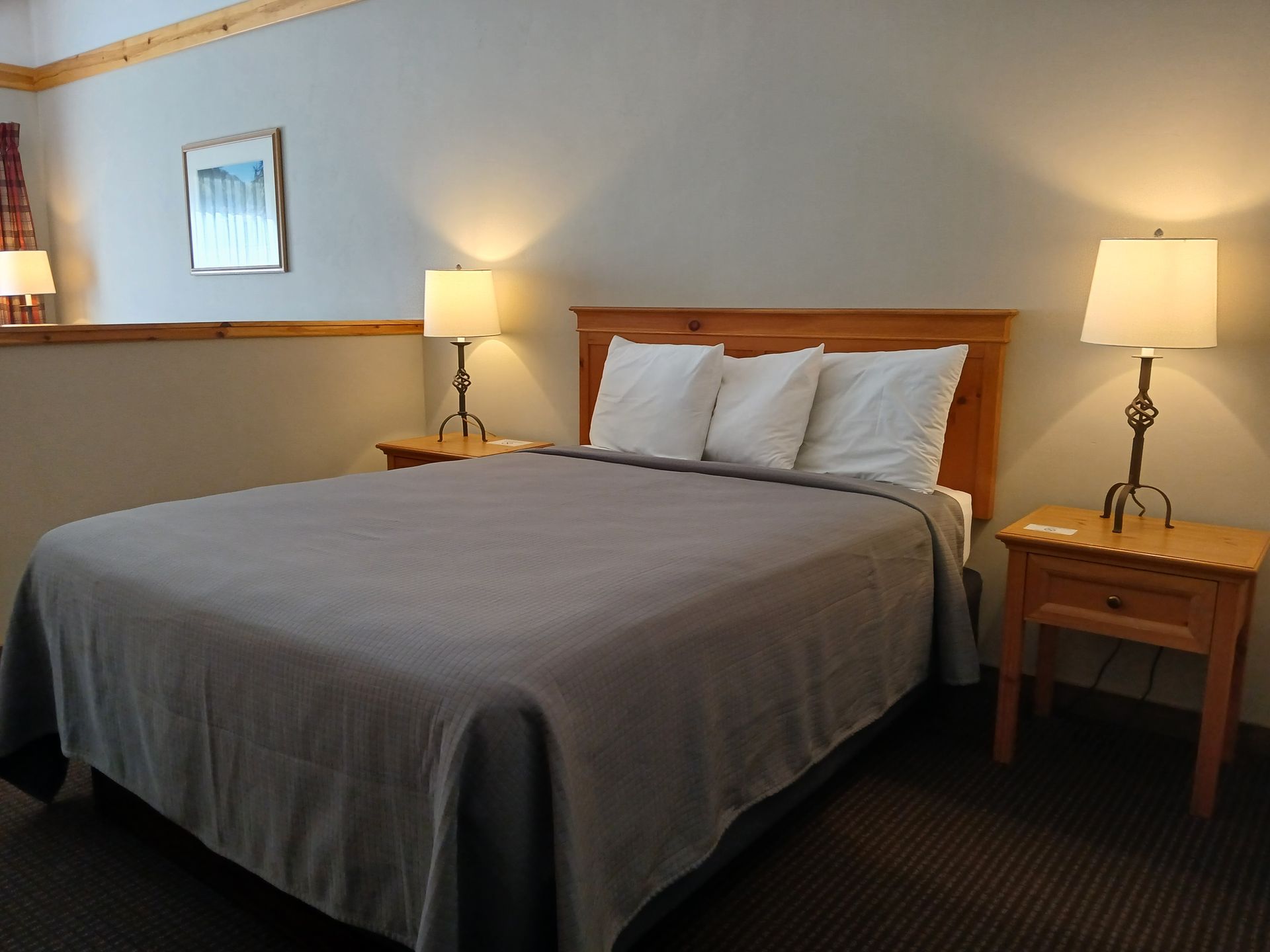 A hotel room with a bed and two lamps