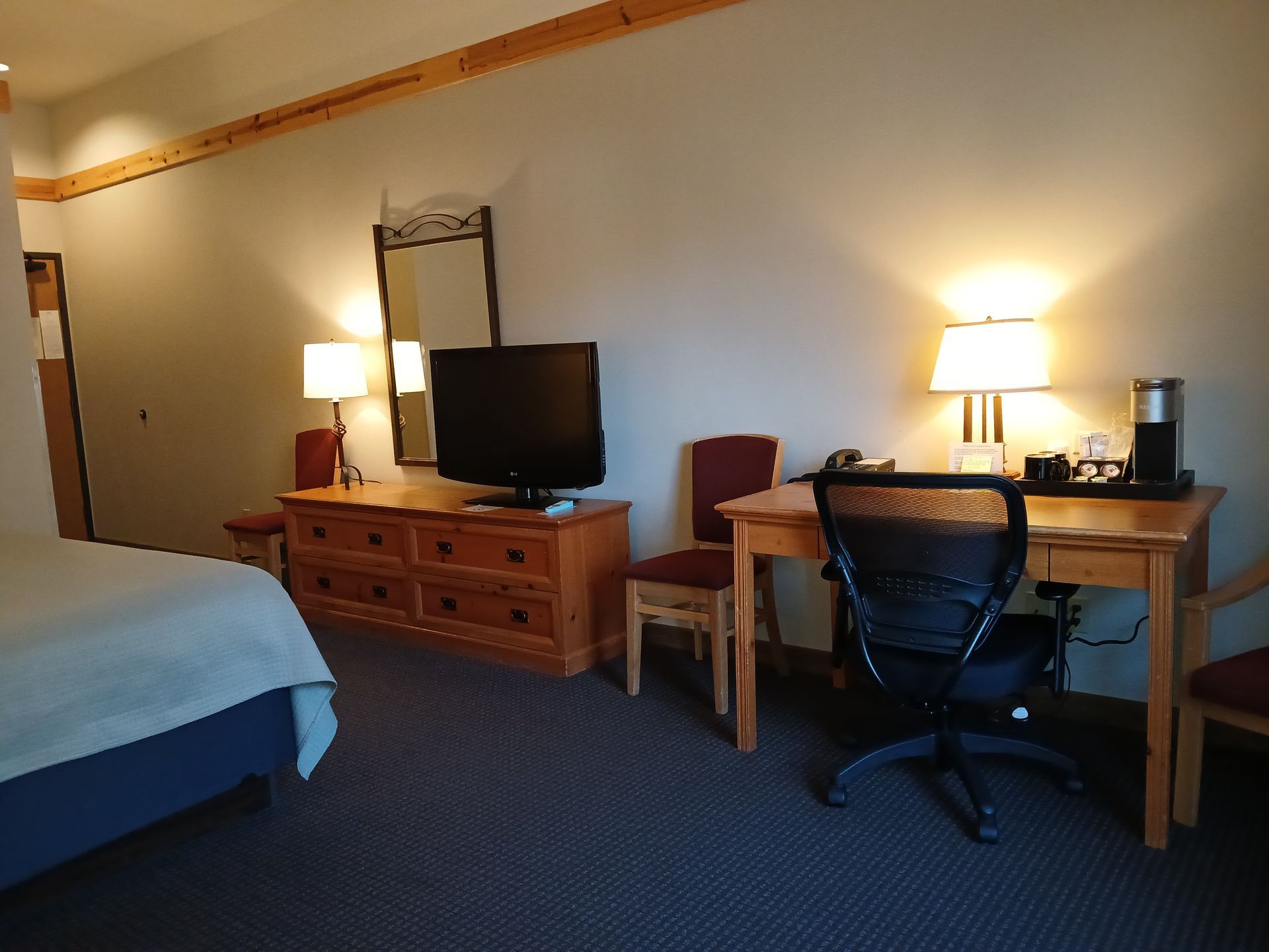 A hotel room with a bed , desk , chair and television