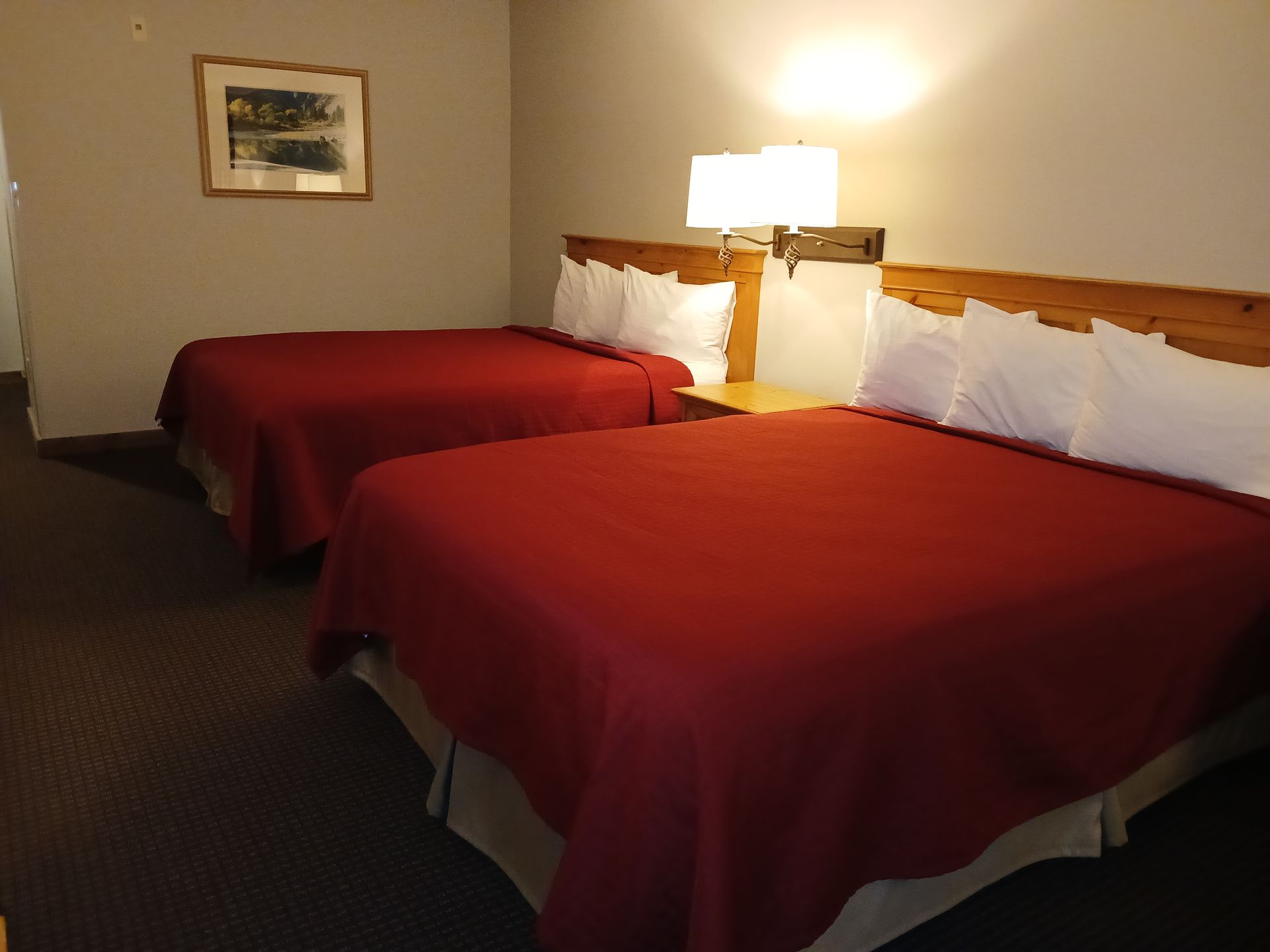 A hotel room with two beds and a picture on the wall