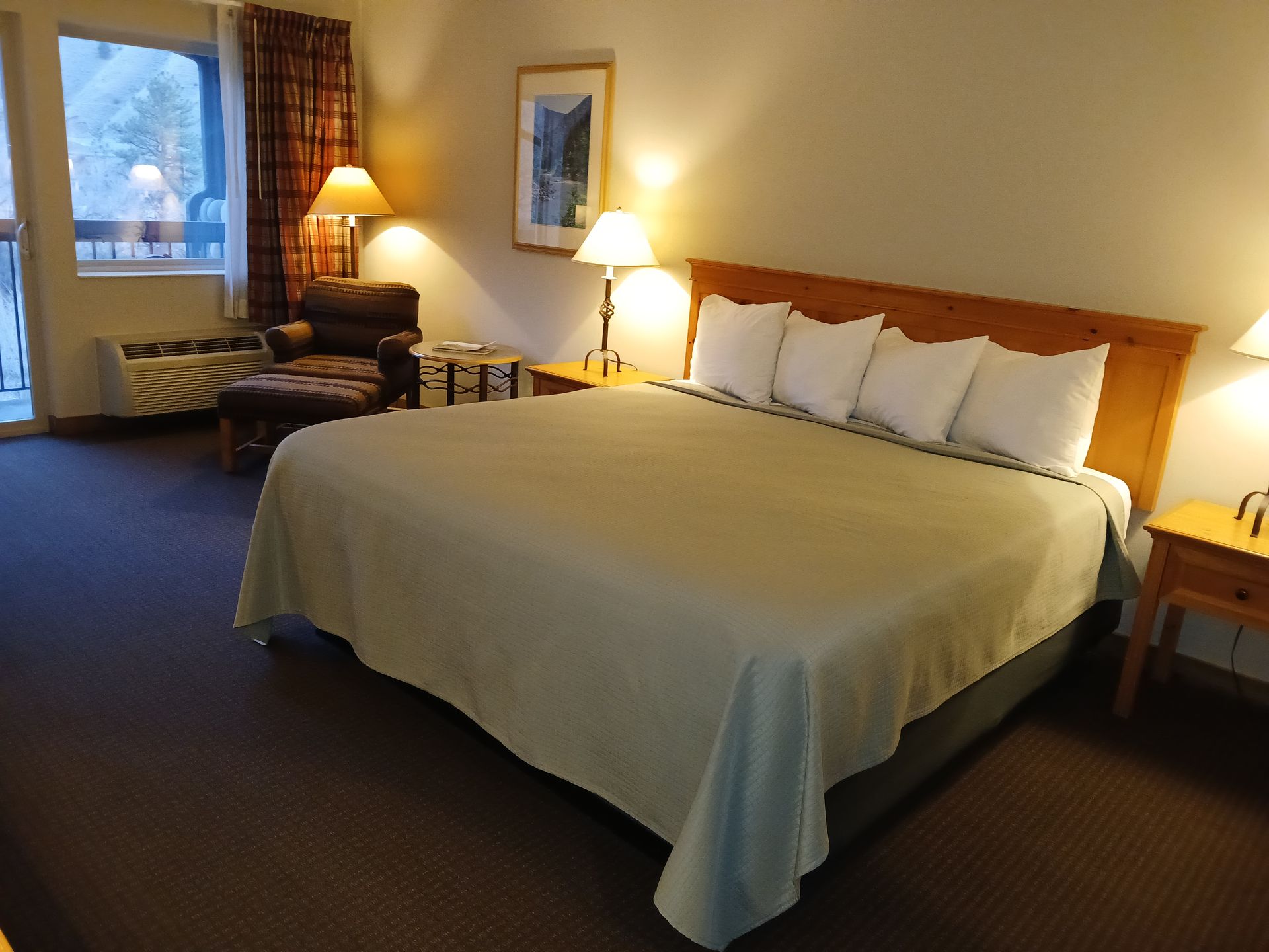 A hotel room with a king size bed and a chair