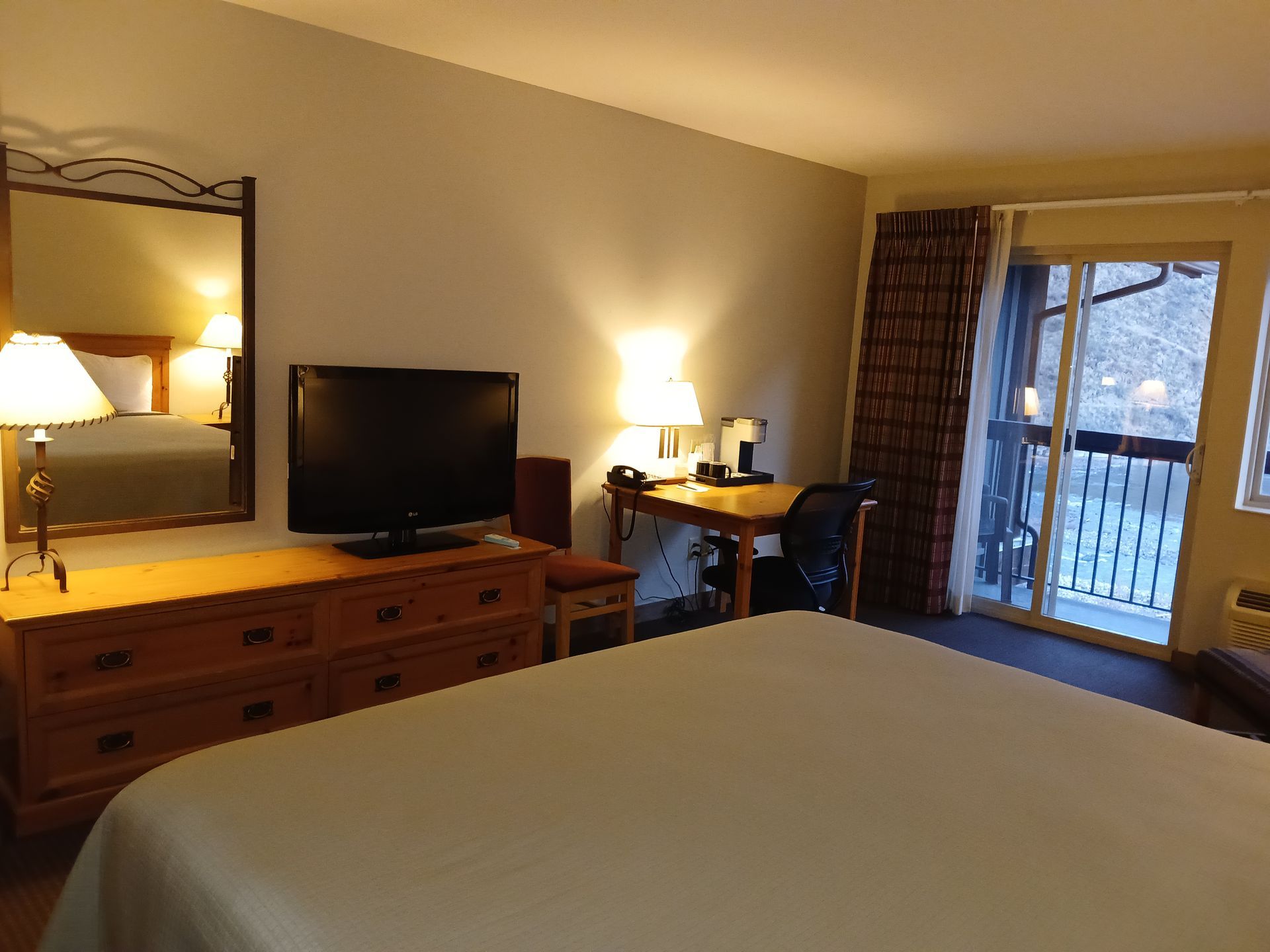 A hotel room with a king size bed and a flat screen tv