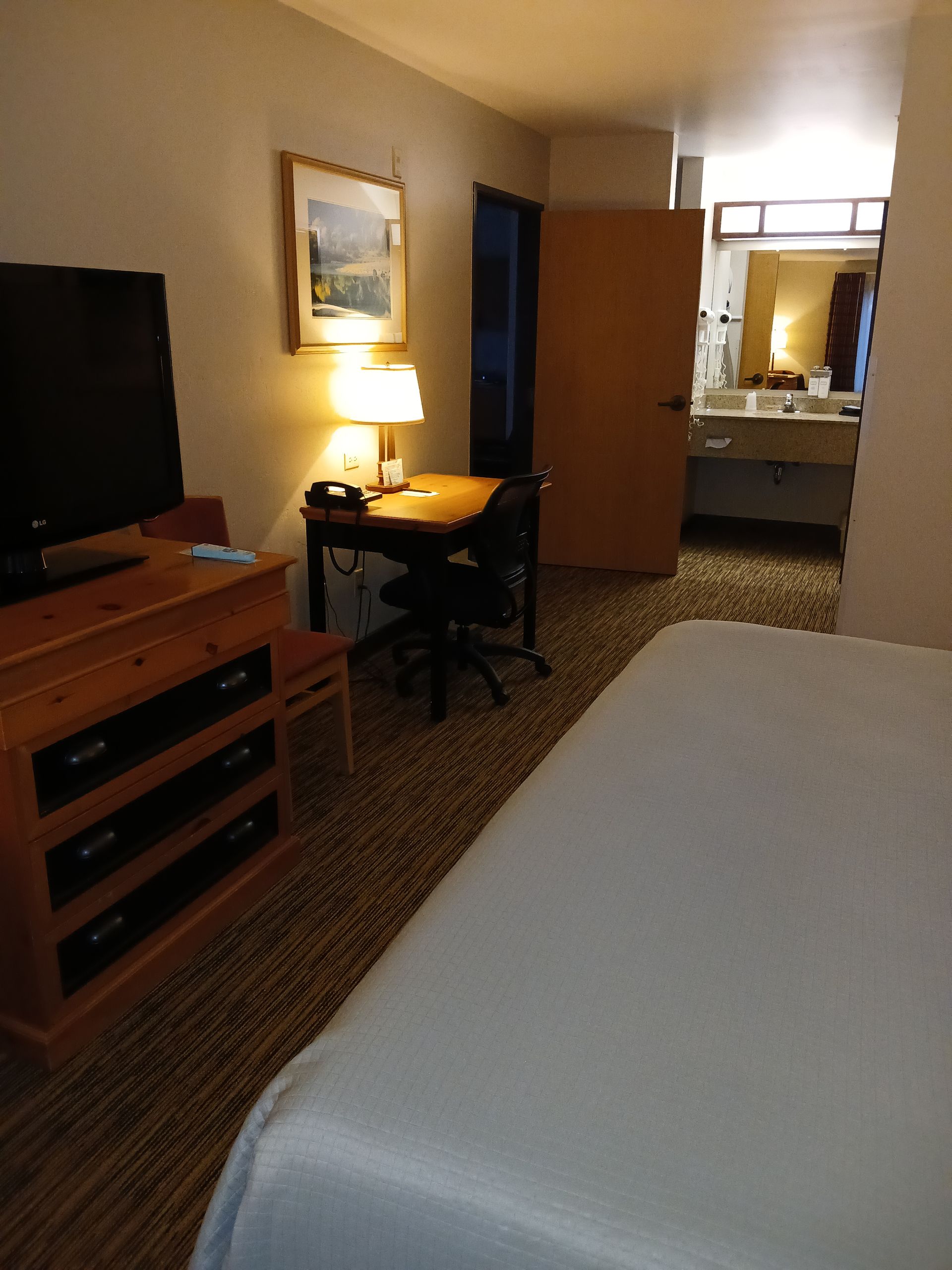 A hotel room with a bed desk and television
