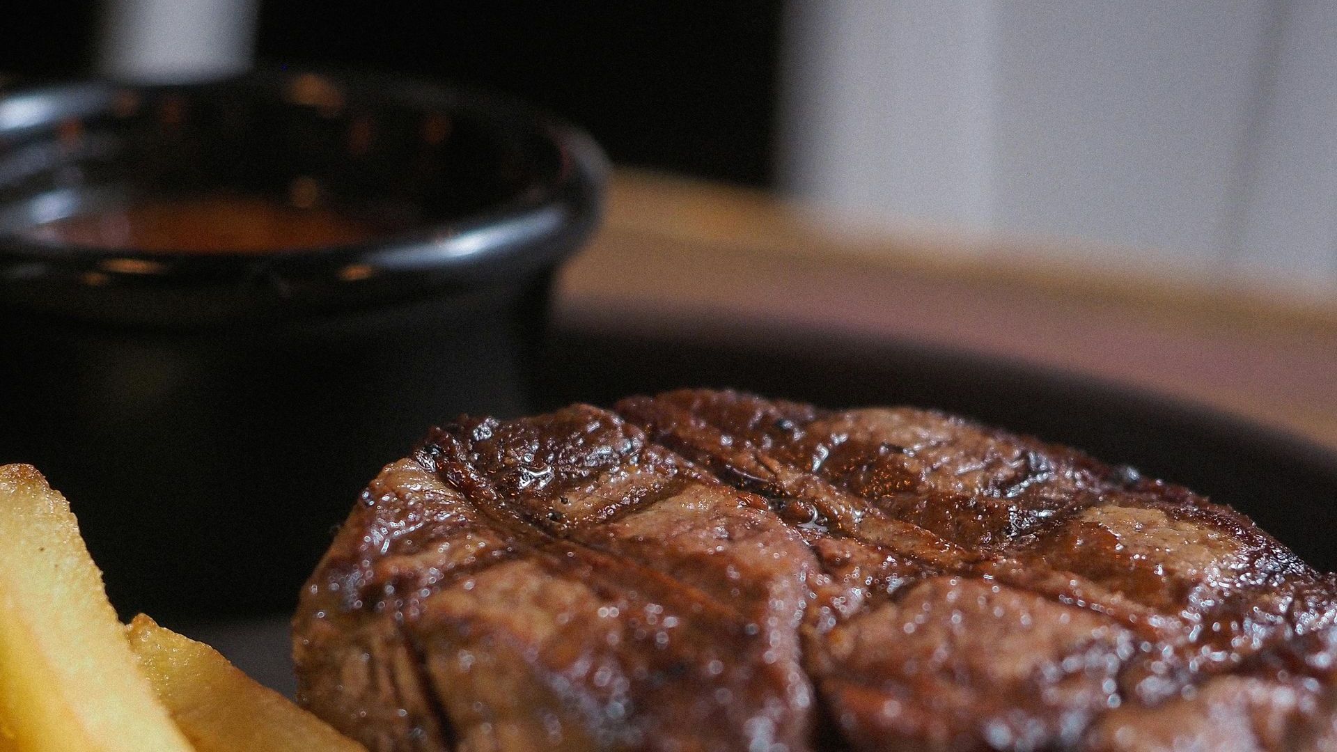 A close up of a steak and french fries on a plate.