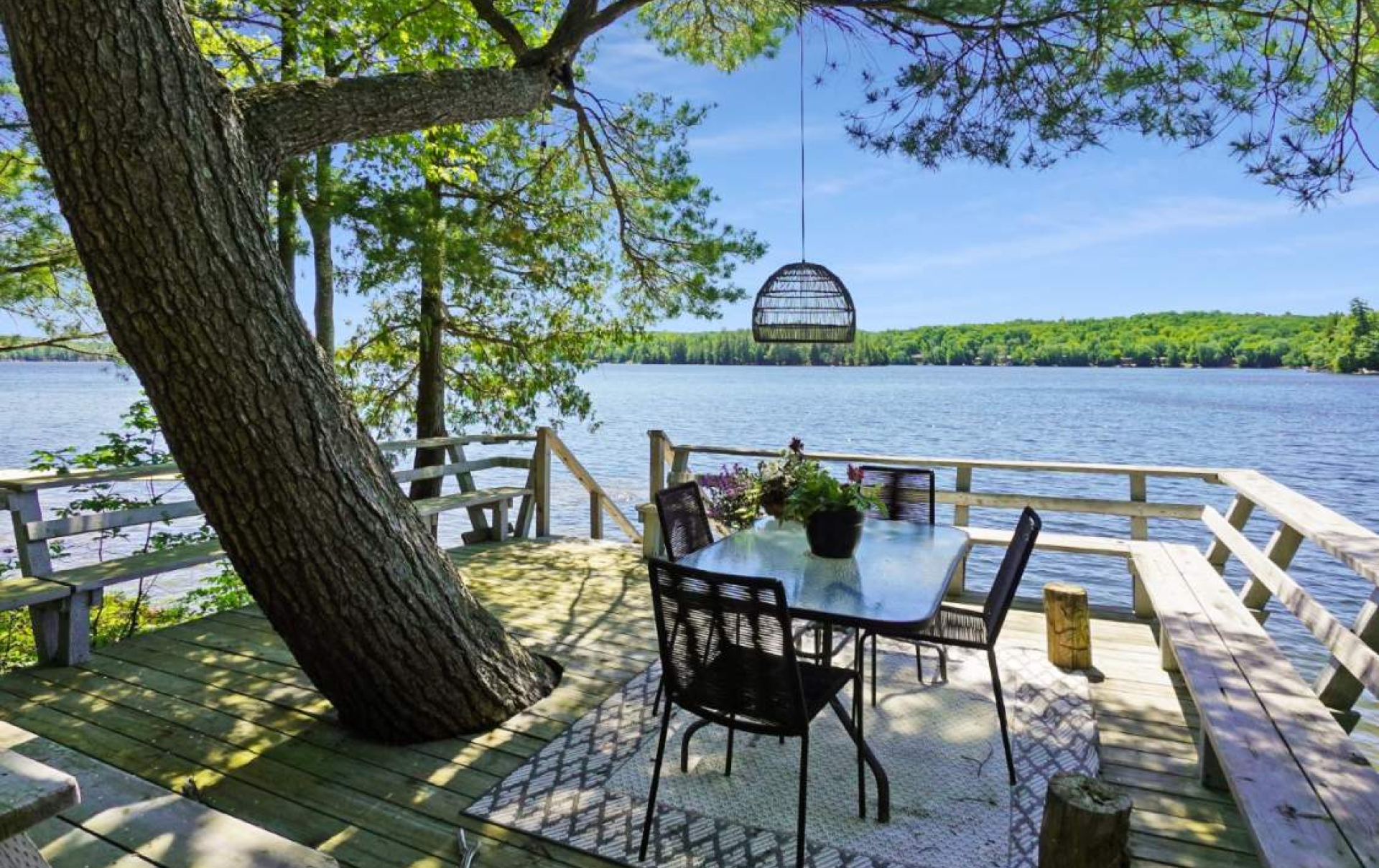 A table and chairs on a dock overlooking a lake.