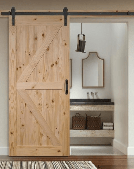 A wooden sliding barn door opens to a bathroom