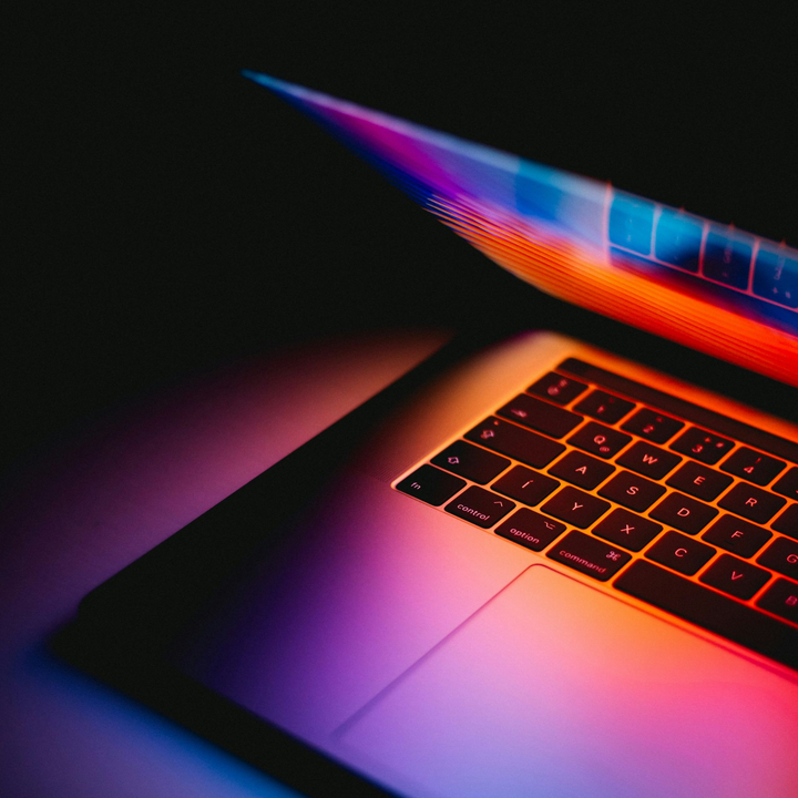 Colorful neon-lit laptop keyboard and trackpad on a dark background