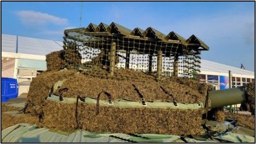 A large pile of hay is sitting on top of a military vehicle