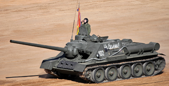 A man is sitting on top of a tank with a flag on top of it.