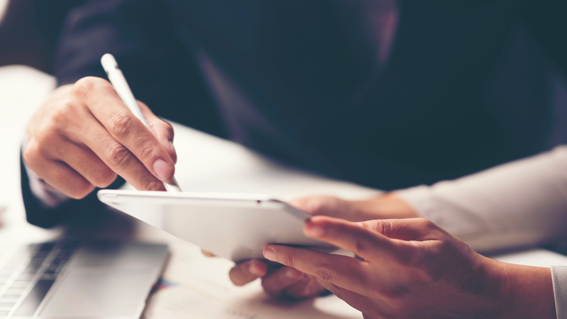 a man is writing on a tablet with a pen .