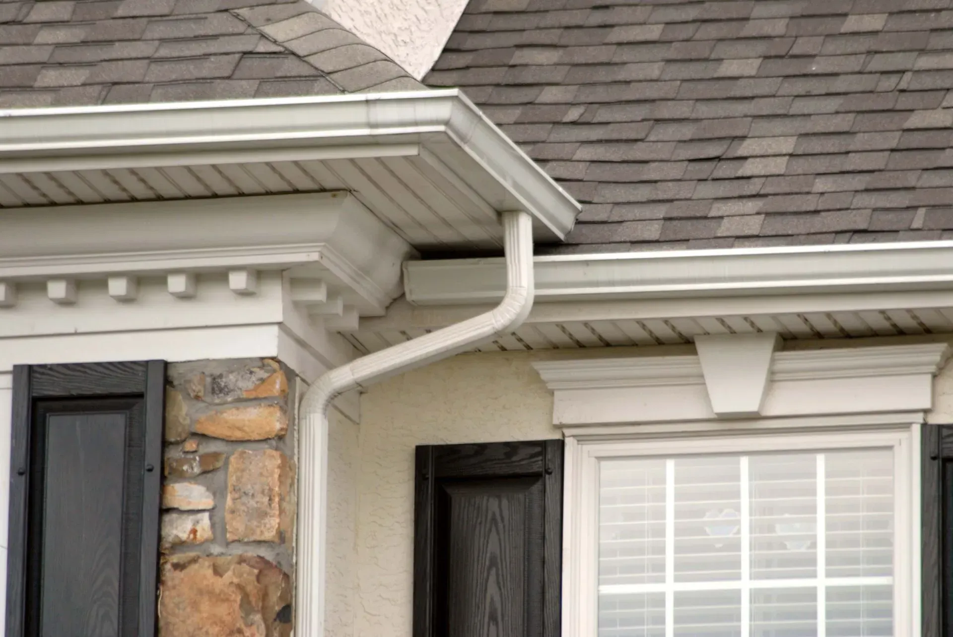 Seamless white gutter and matching downspout installation on a home in St. Charles County.