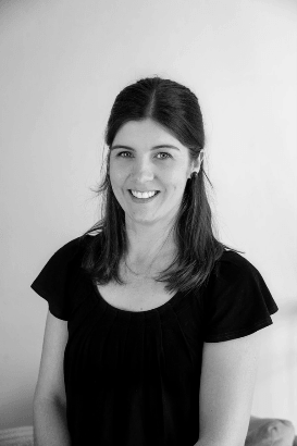 A woman in a black shirt is smiling in a black and white photo.