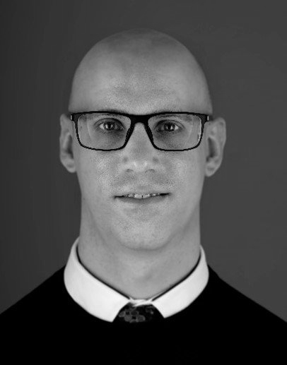 A black and white photo of a bald man wearing glasses