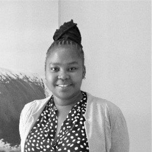 A woman in a polka dot shirt and cardigan is smiling in a black and white photo.
