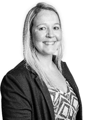 A black and white photo of a woman wearing a jacket and smiling.