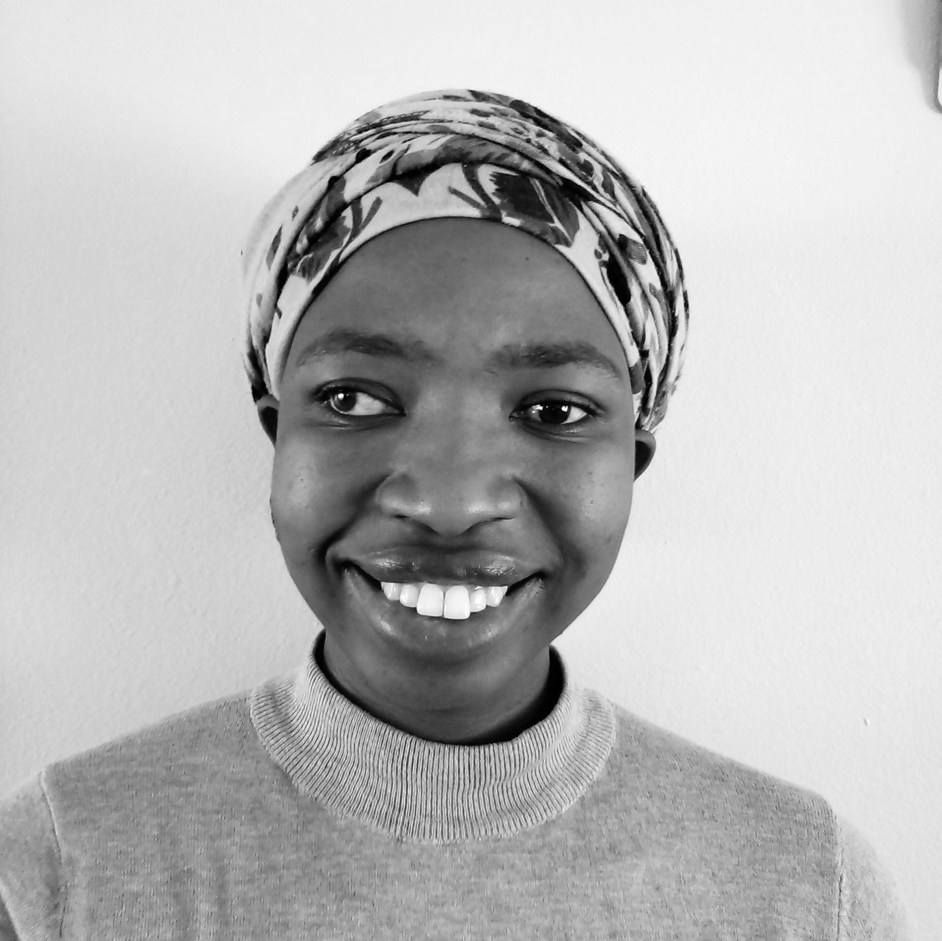 A woman wearing a head scarf is smiling in a black and white photo