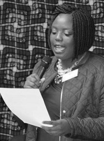 A woman is holding a microphone and reading a piece of paper.
