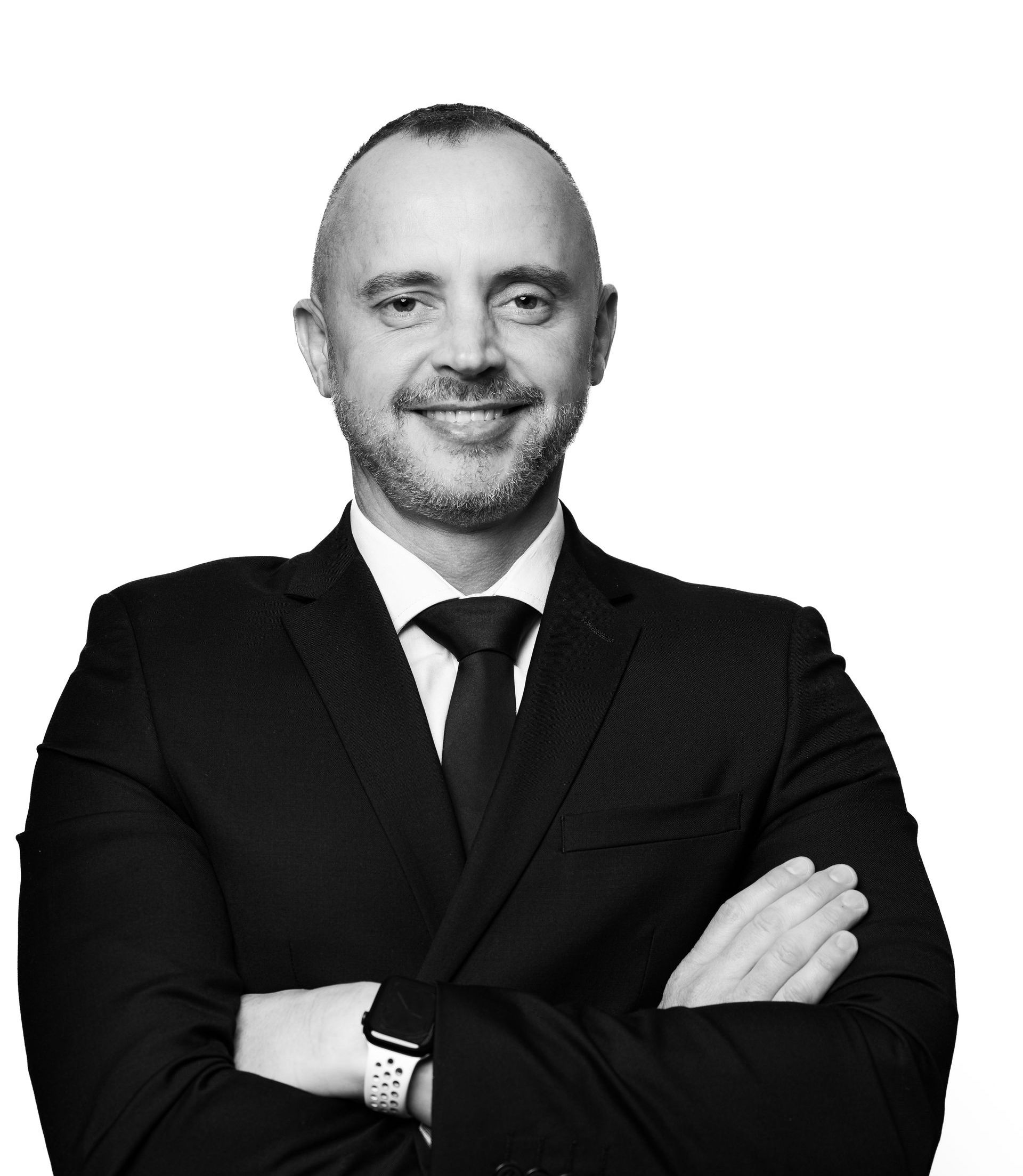 A man in a suit and tie is smiling with his arms crossed.