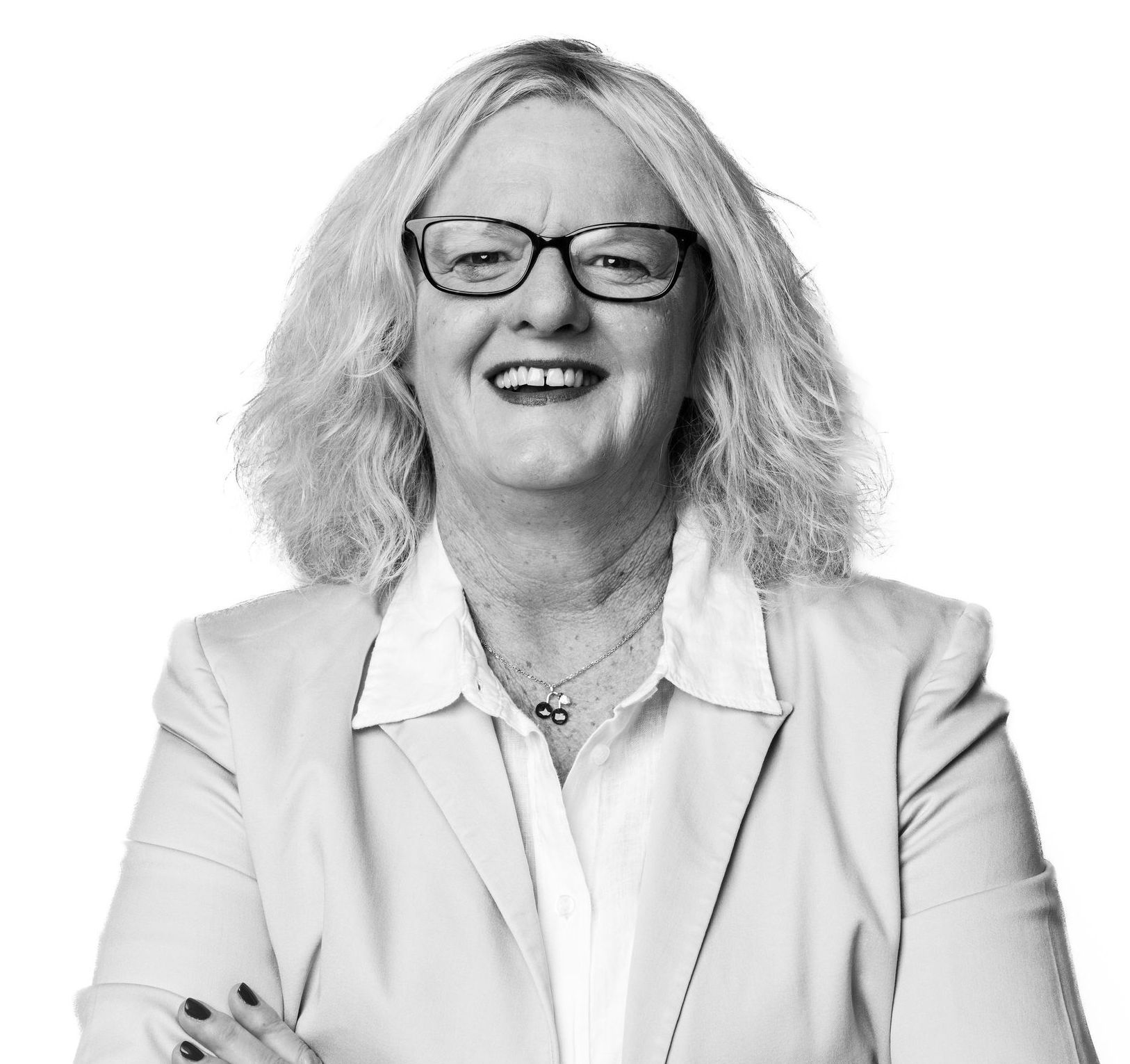 A woman wearing glasses and a white shirt is smiling in a black and white photo.