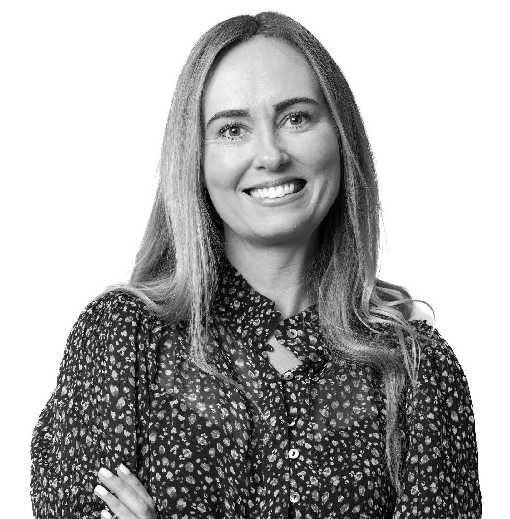 A woman in a floral shirt is smiling in a black and white photo.