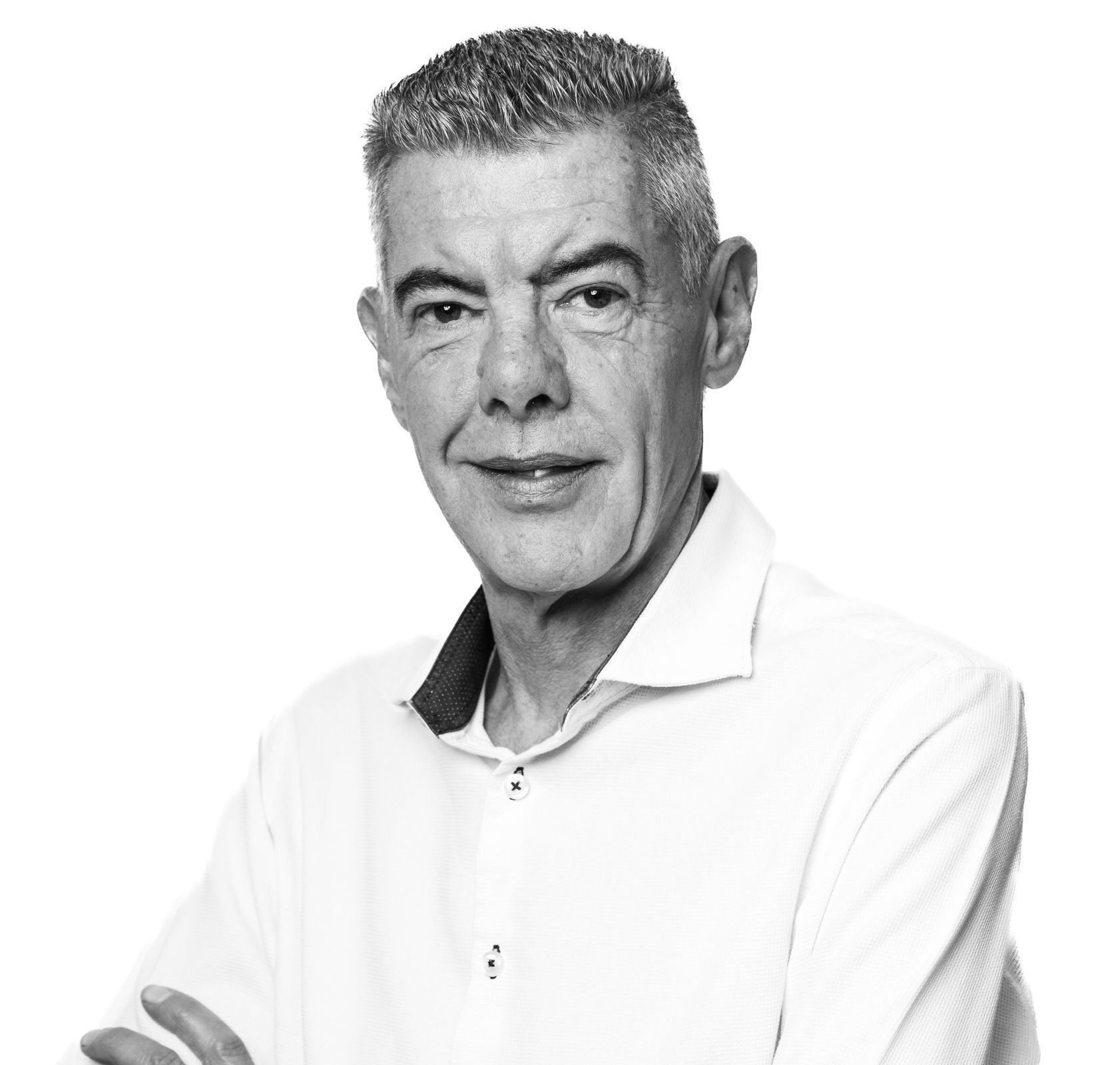 A black and white photo of a man in a white shirt with his arms crossed.