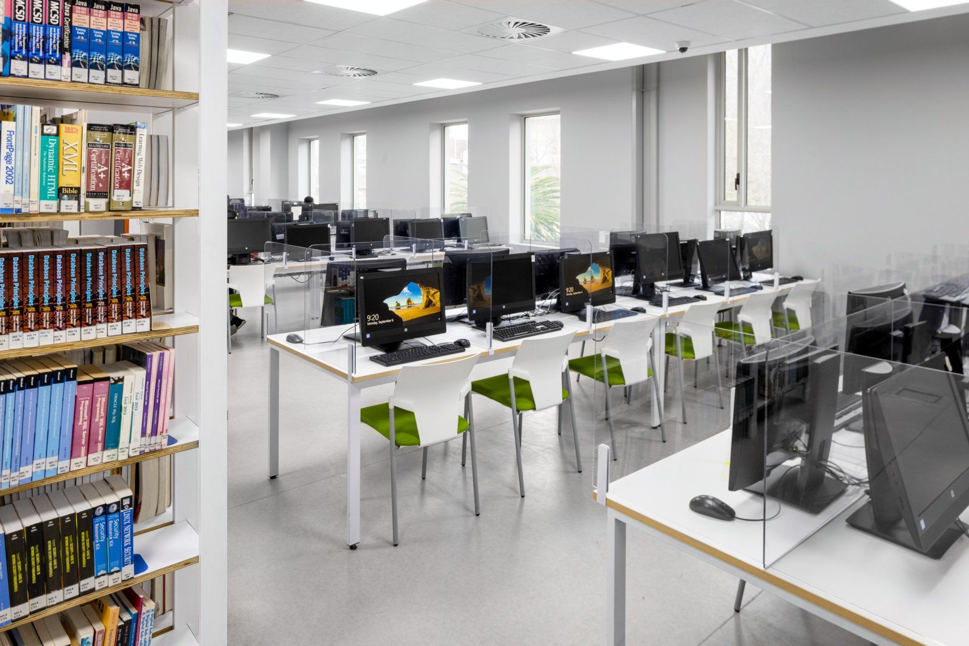 A library with a lot of computers and shelves of books.