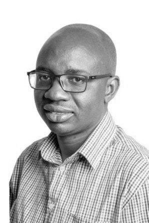A black and white photo of a man wearing glasses and a plaid shirt.