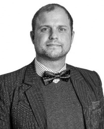 A man in a suit and bow tie is standing in front of a white background.