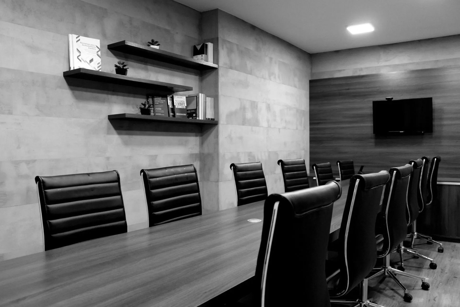 A black and white photo of a conference room with a long table and chairs.