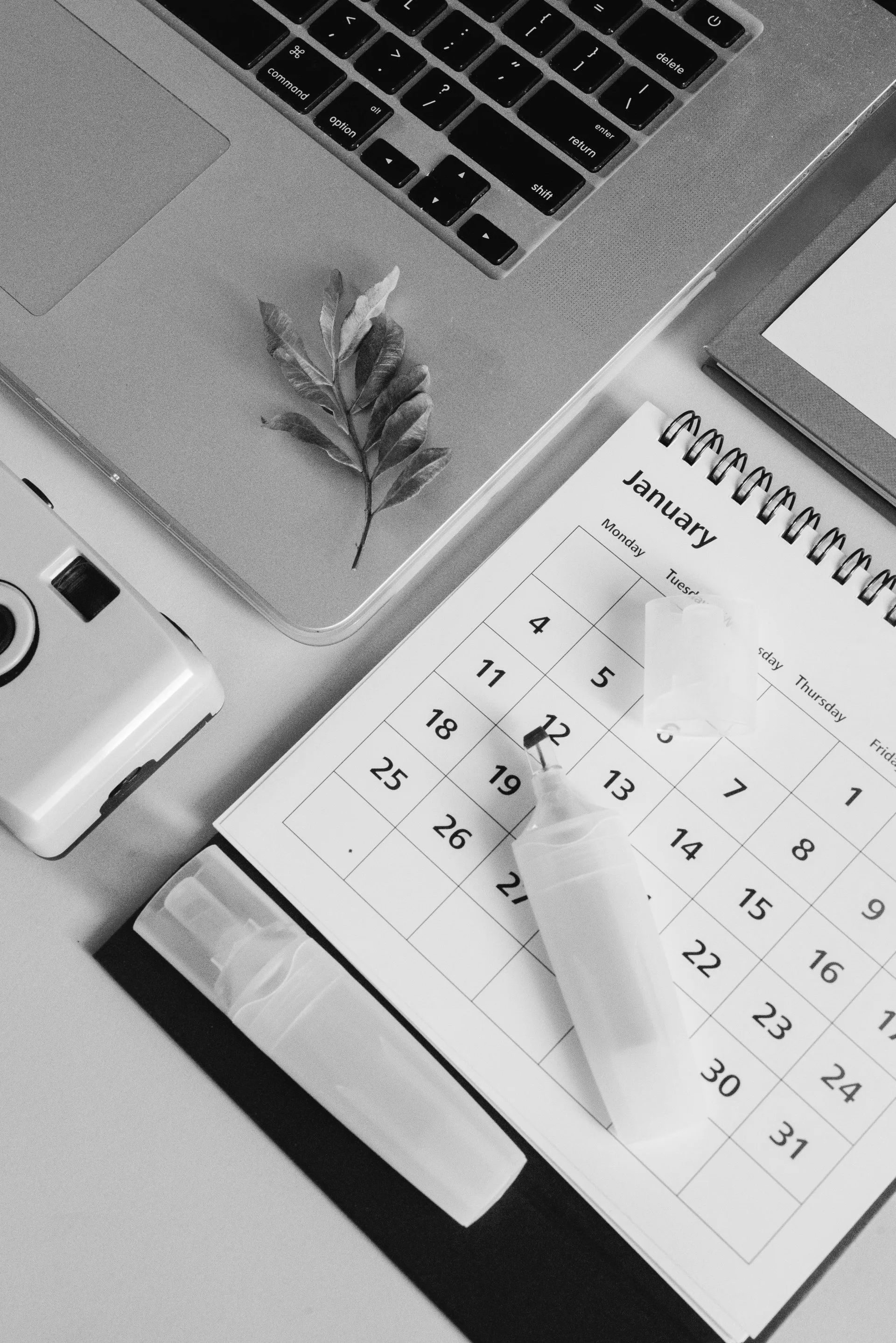 A black and white photo of a calendar next to a laptop