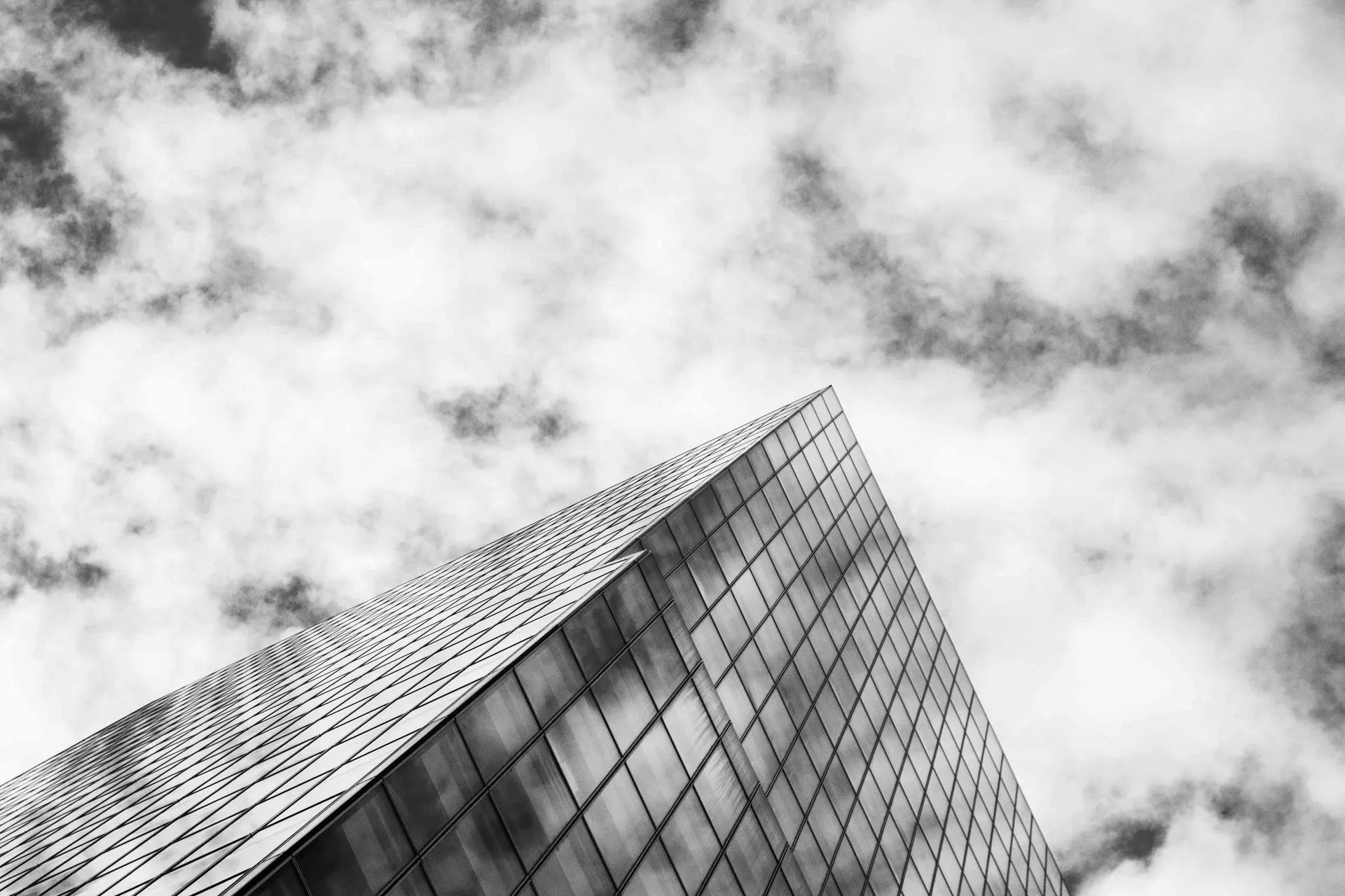 A black and white photo of a tall building against a cloudy sky.