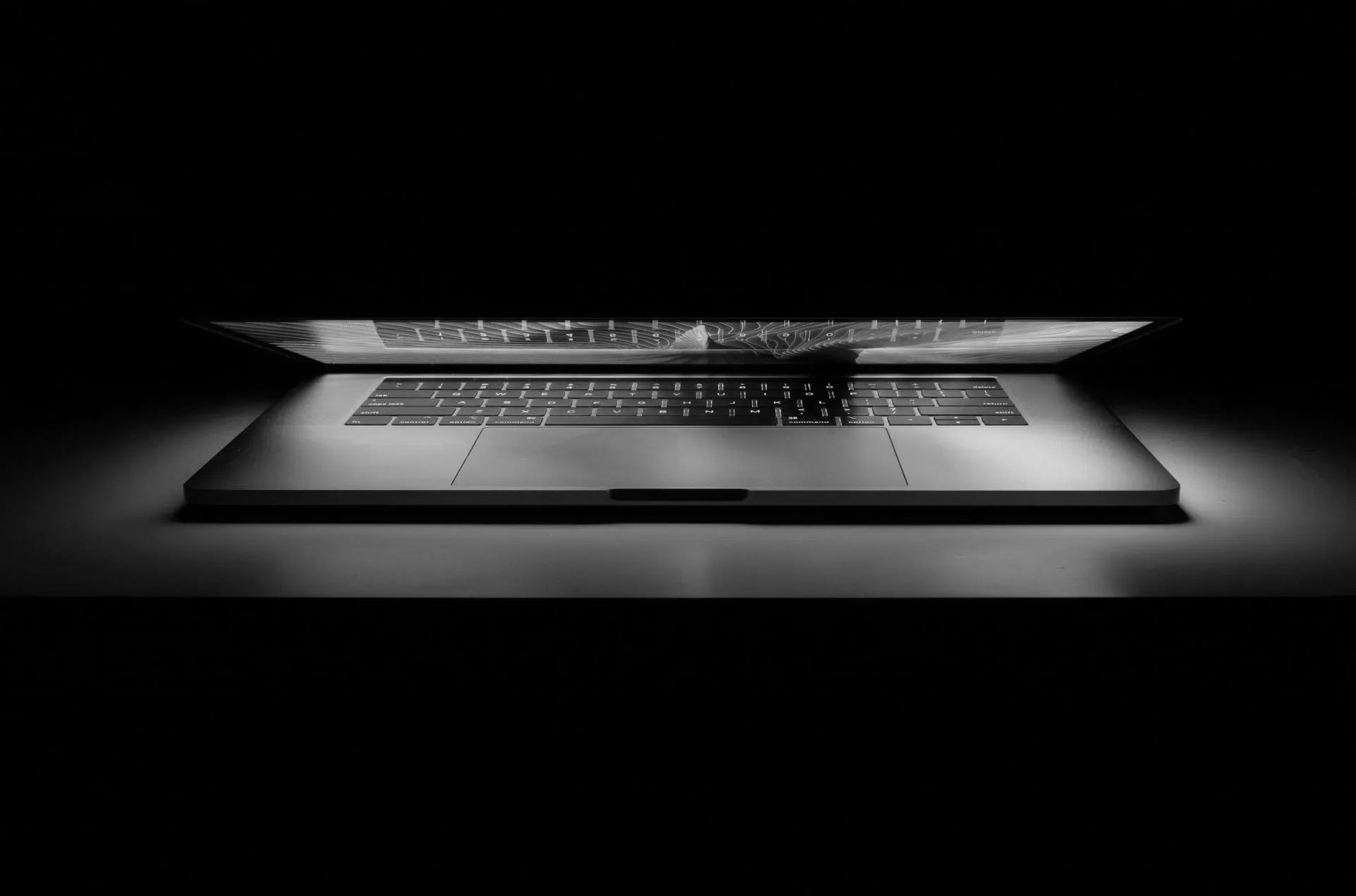 A black and white photo of a laptop computer on a table.
