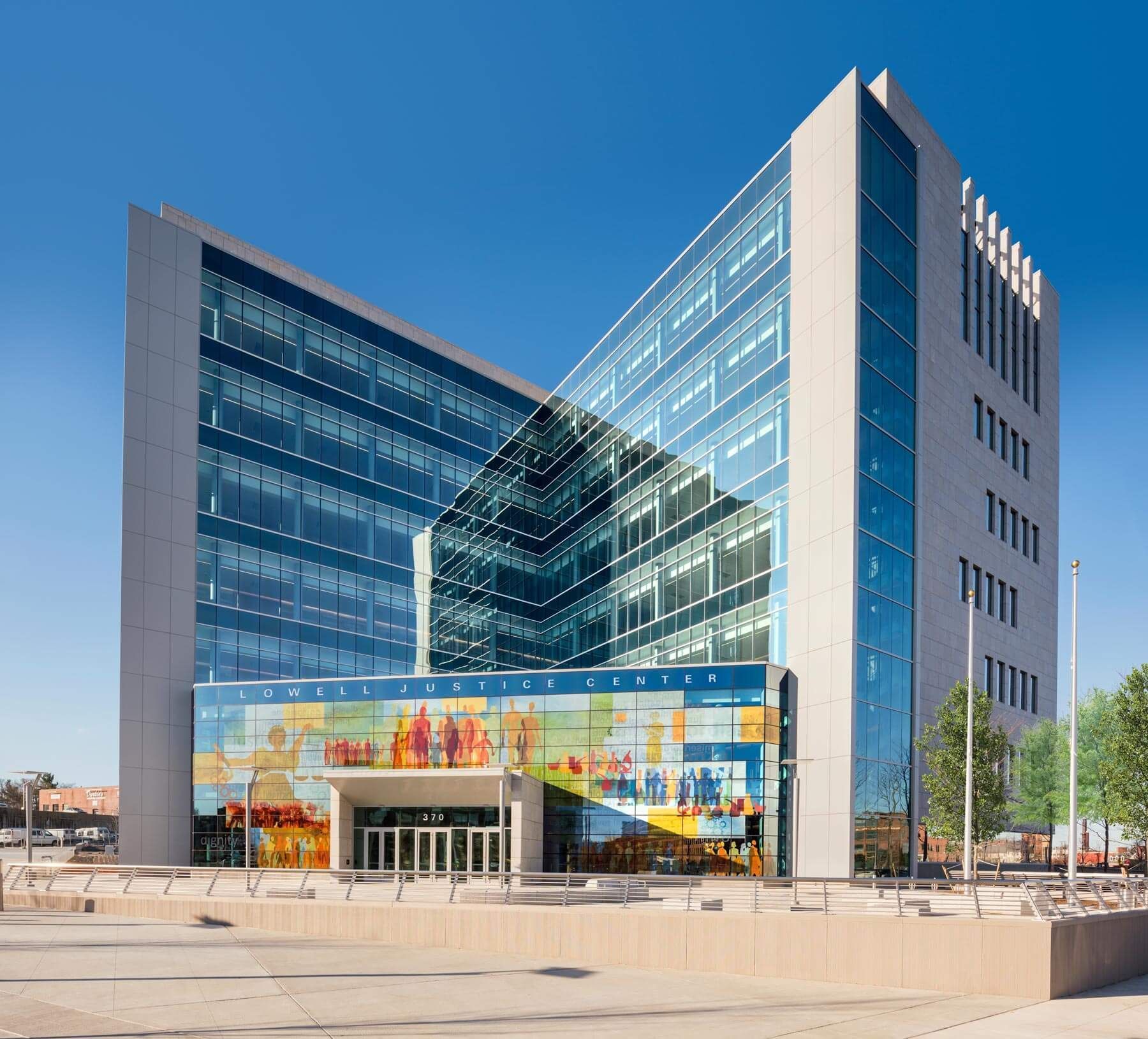 Modern glass office building with colorful mural and entrance plaza under a blue sky