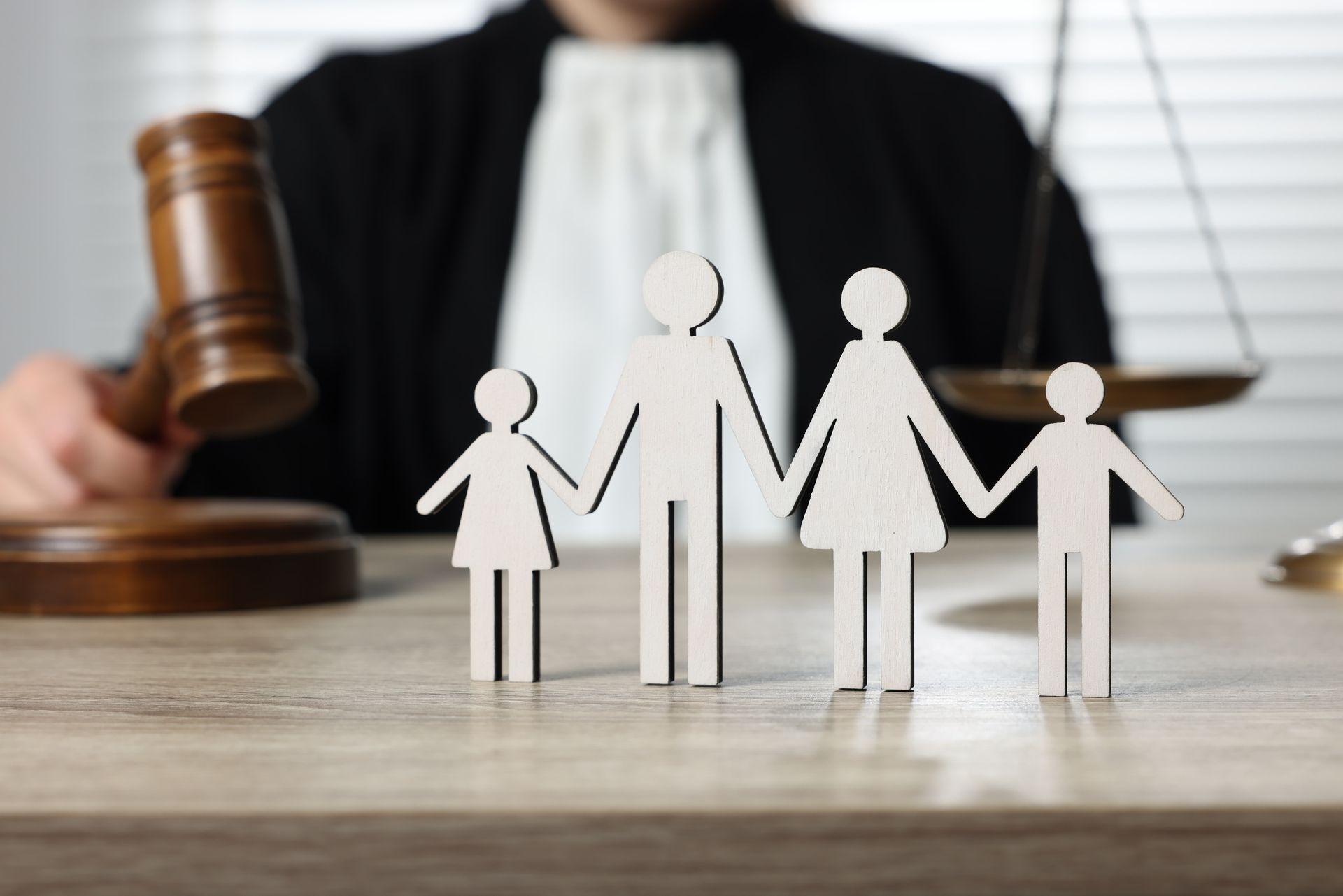 Legal family concept figures in front of a judge’s gavel and scales of justice