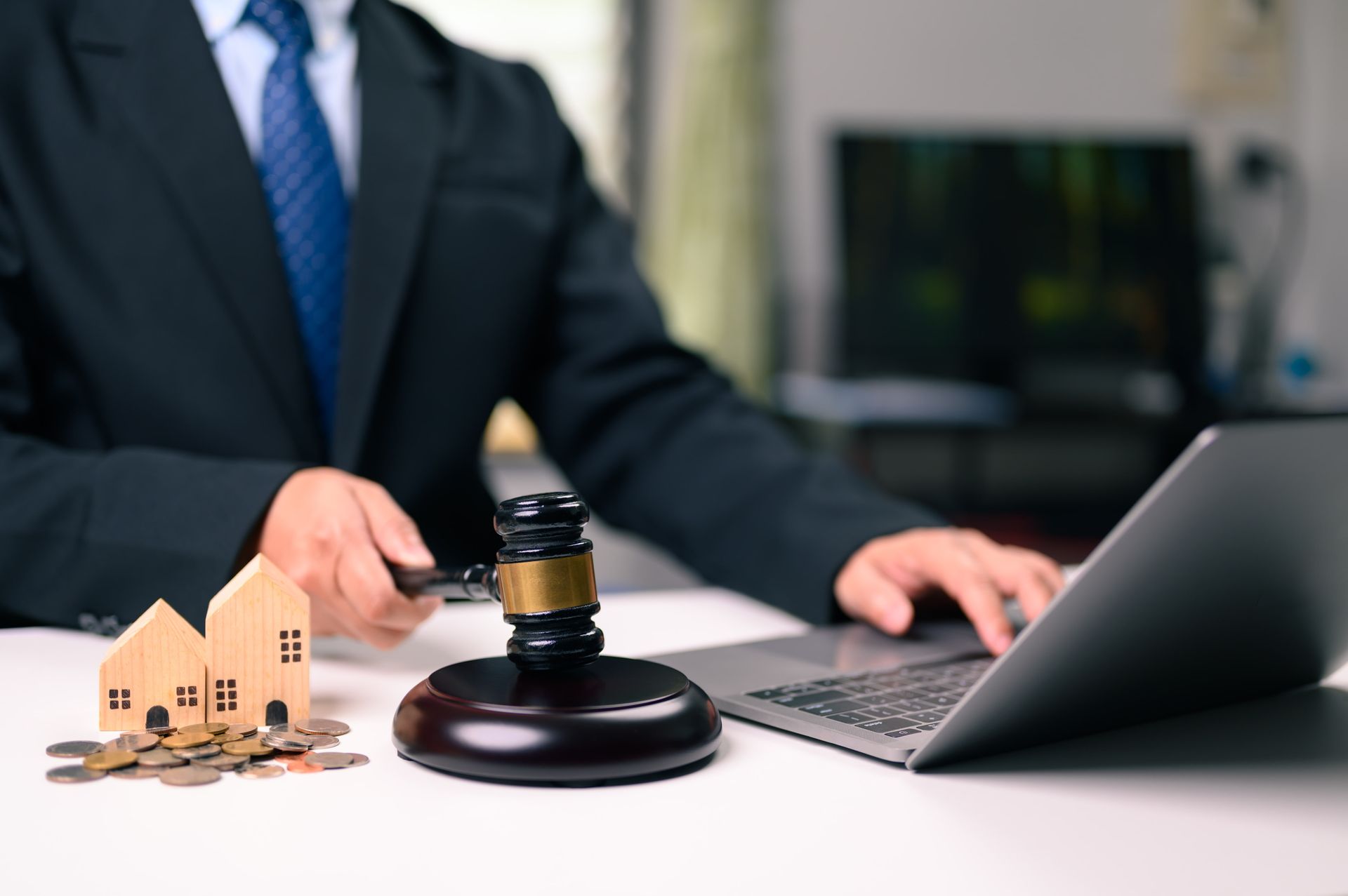 Lawyer at desk with gavel, house model, and laptop during real estate contract review