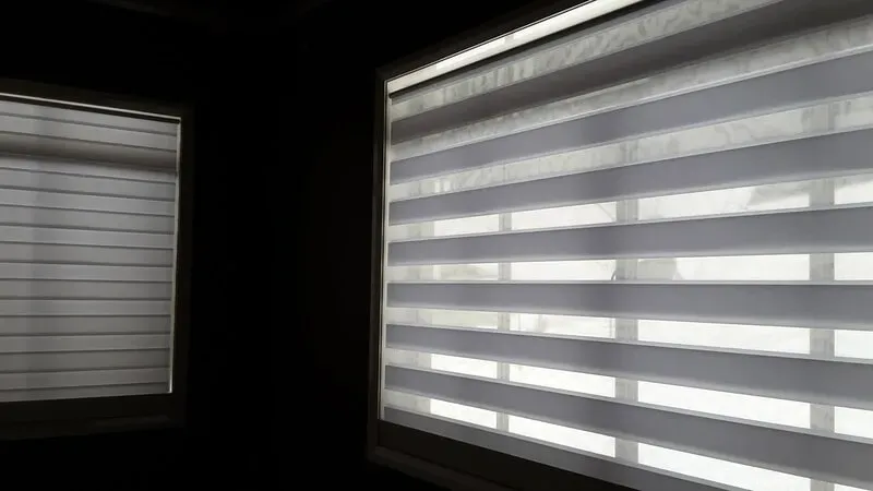 A Couple of Blinds Are Hanging on a Window in a Dark Room — Aussie Carpets & Vinyl In Beerwah, QLD